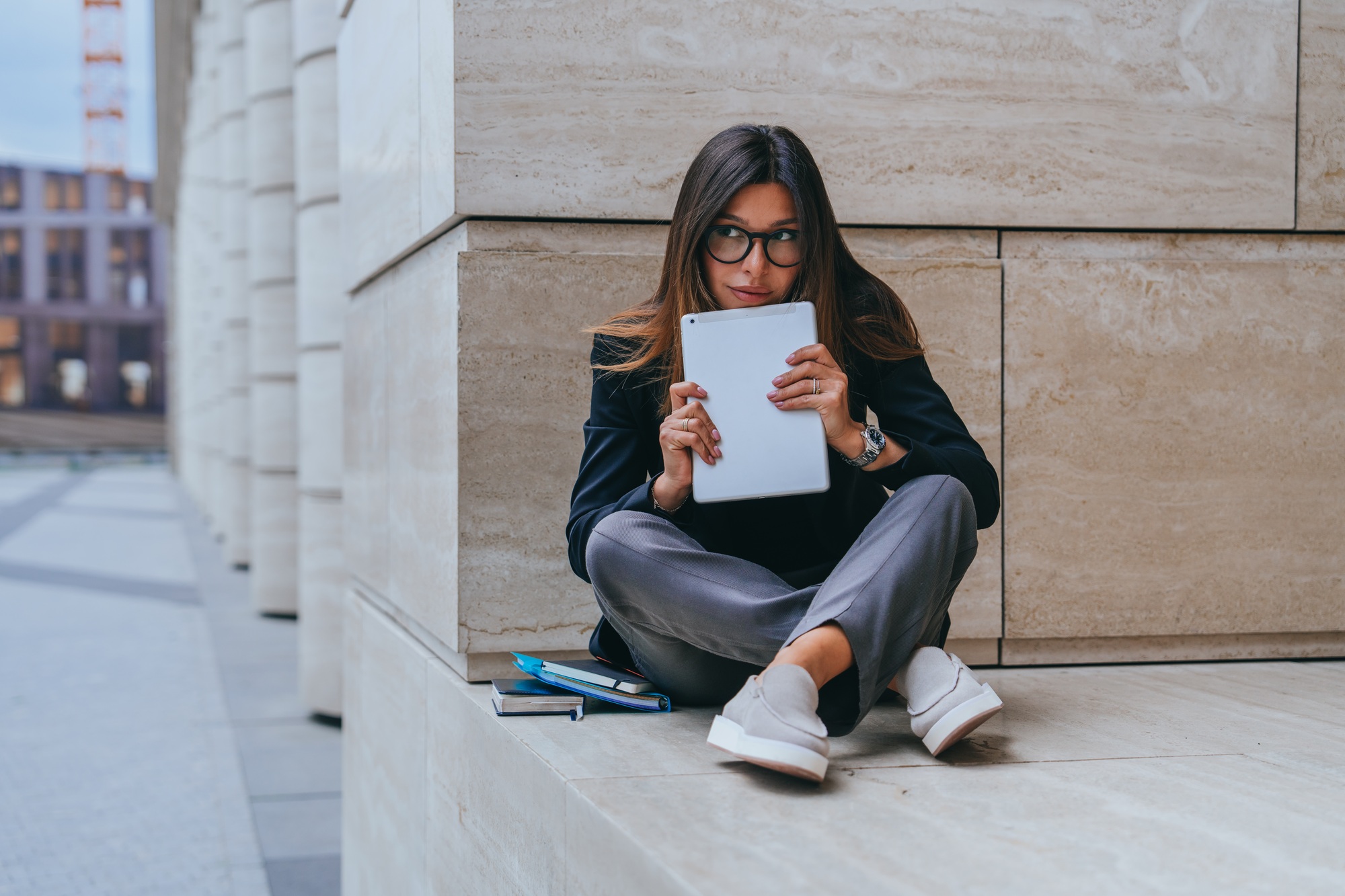 Businesswoman with tablet sitting on steps, deep in thought