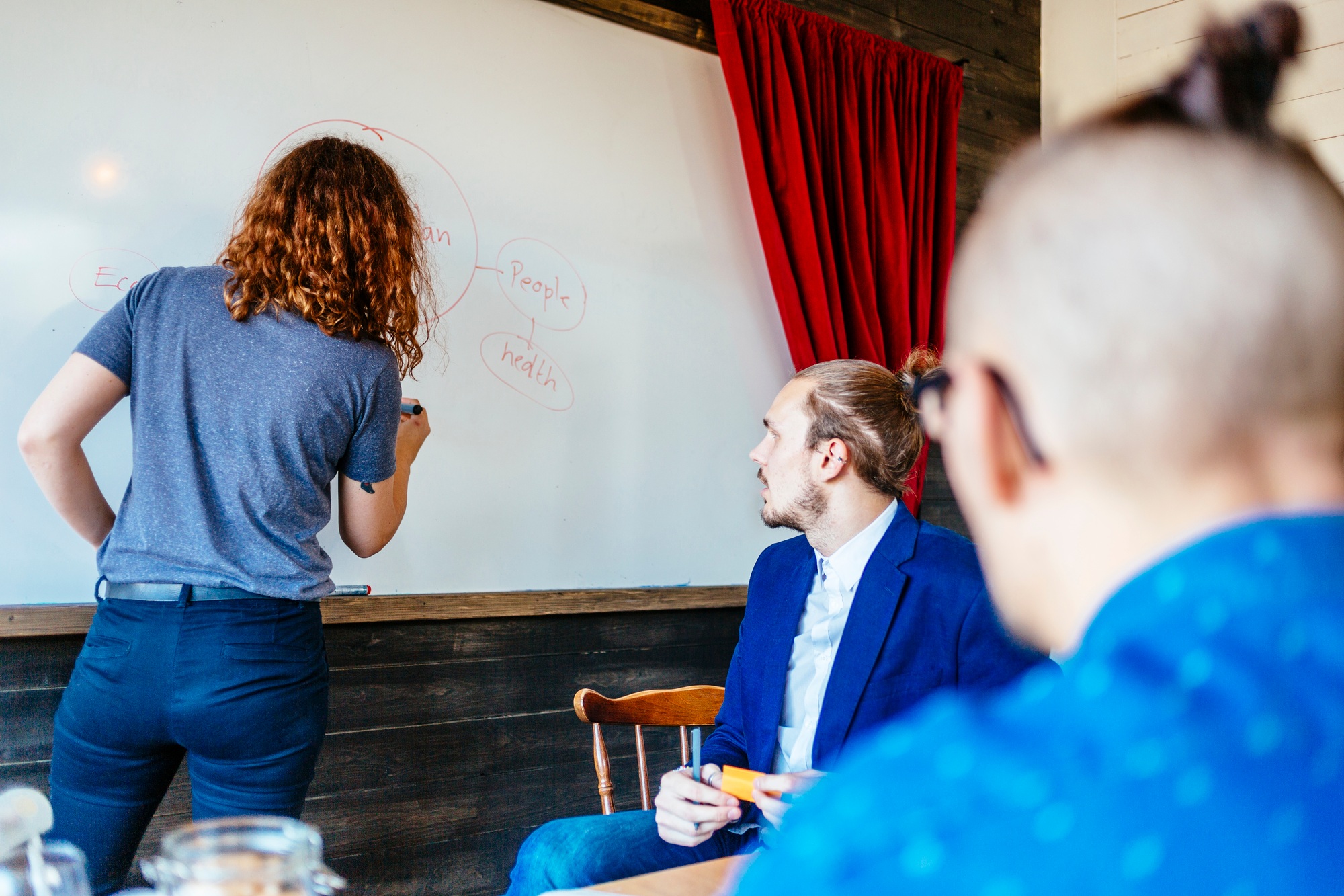 Businesswoman writing on whiteboard leading meeting in board room