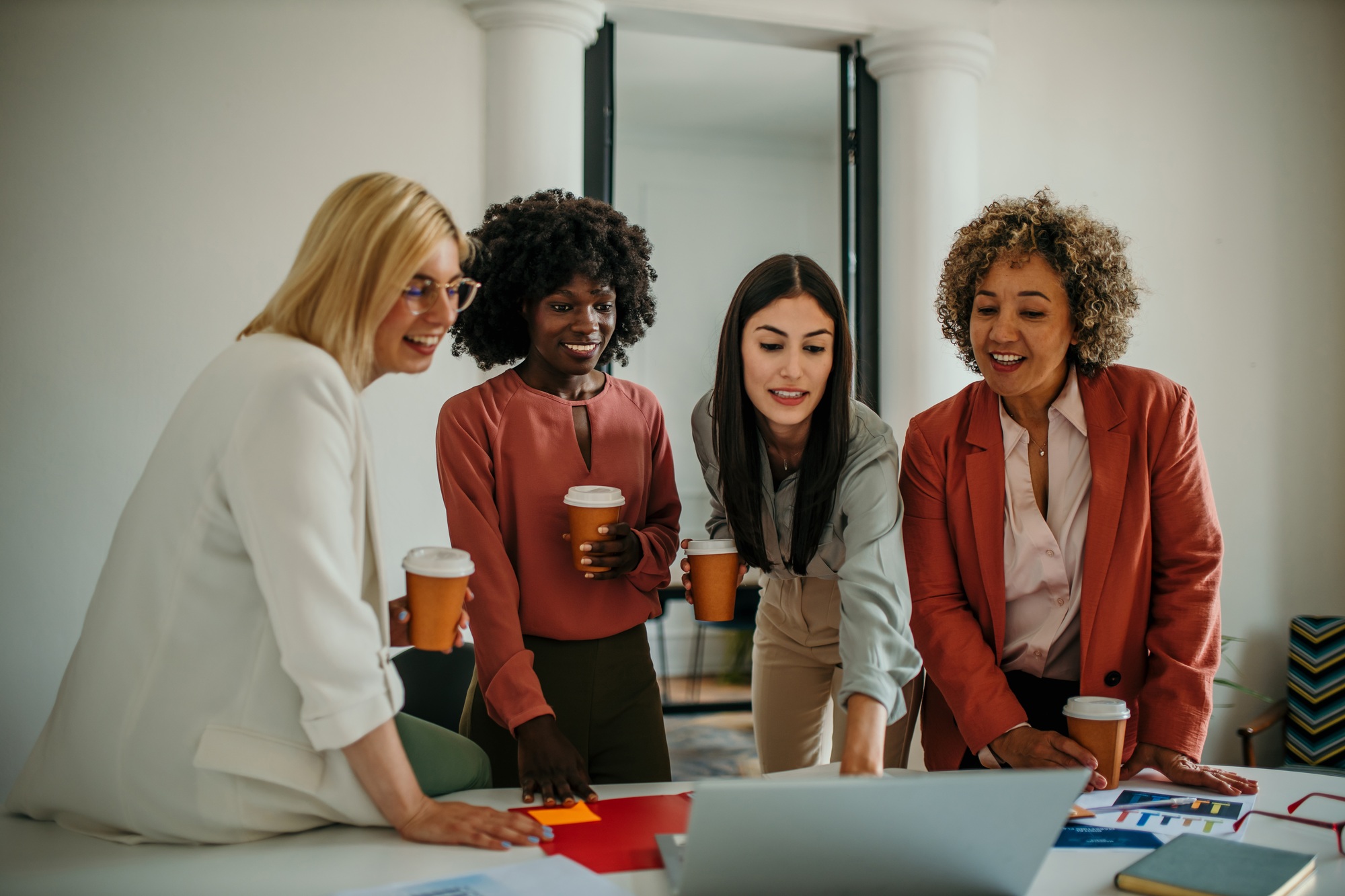 Businesswomen having meeting using laptop and drinking coffee