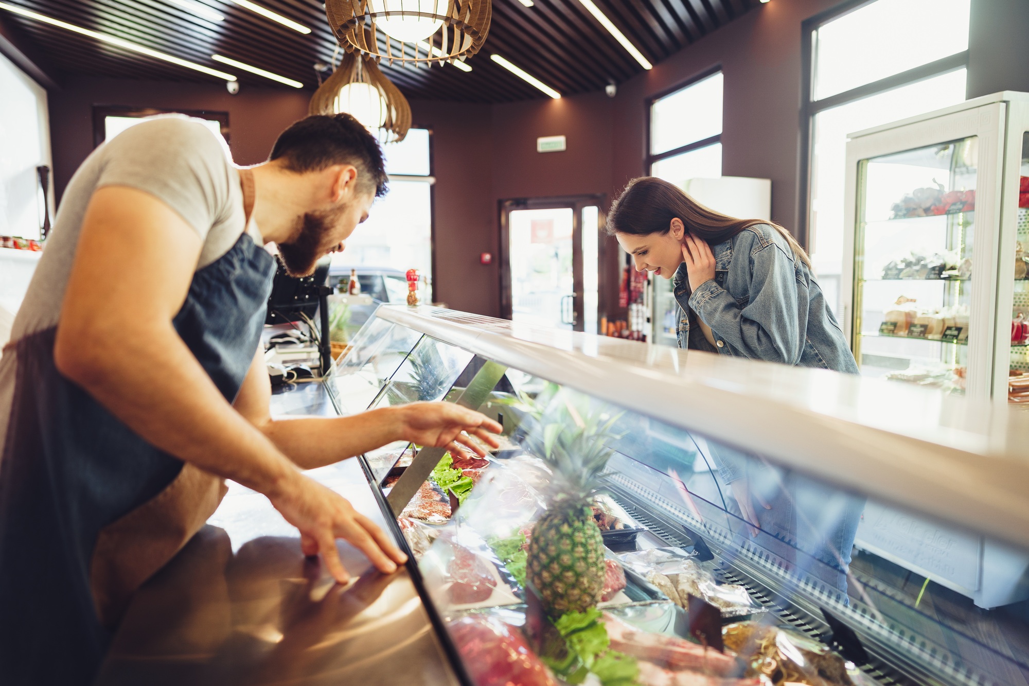 Butcher's shop seller helps to choose product to woman customer