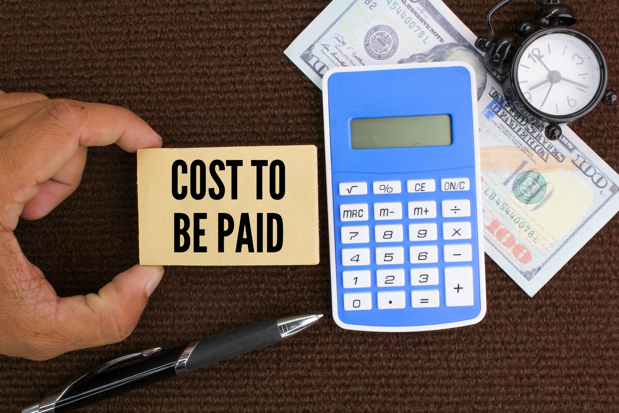calculator, pen and paper money with the word cost to be paid.