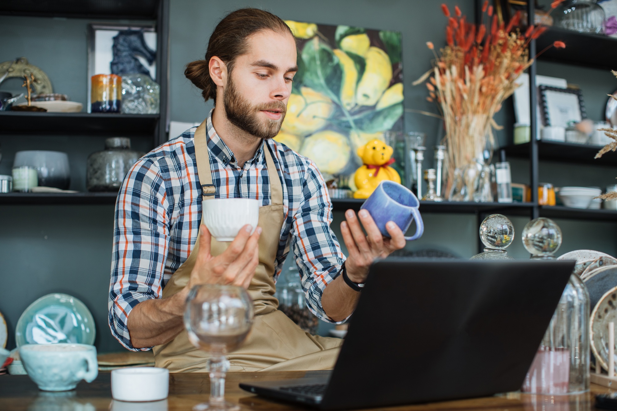 Caucasian man doing inventory at decor store with laptop