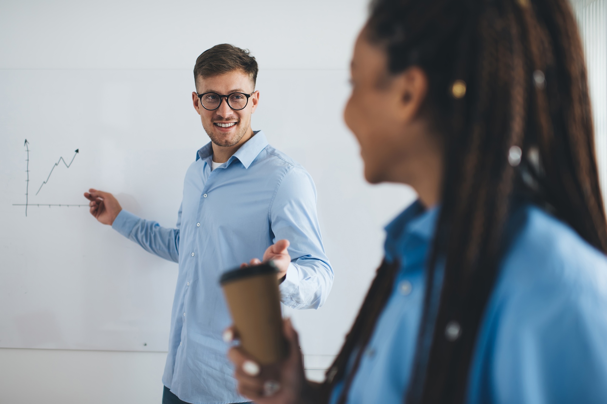 Caucasian professional employee in eyewear explaining infographics charts in board room