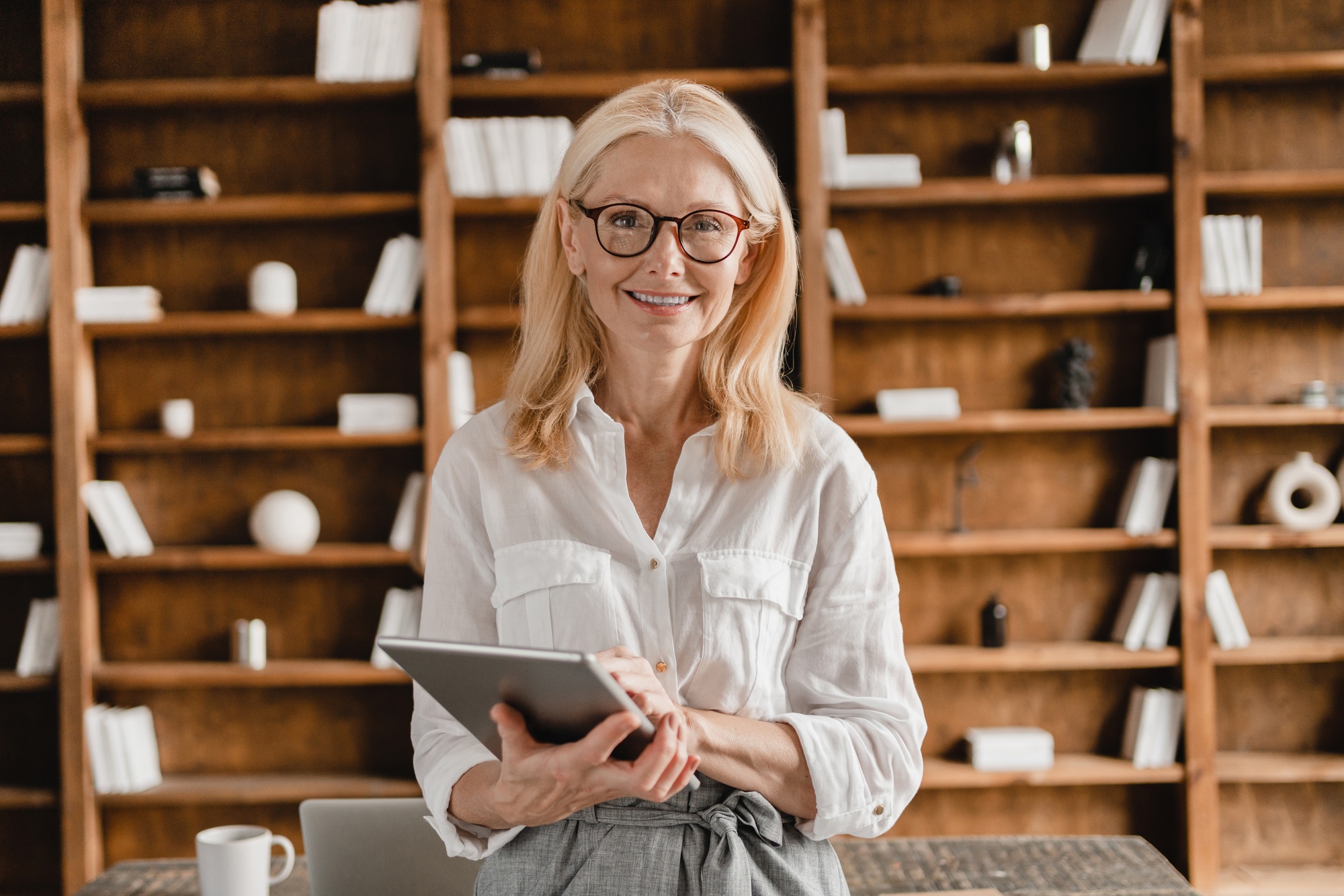 Ceo holding digital tablet looking at the camera while working remotely in home office
