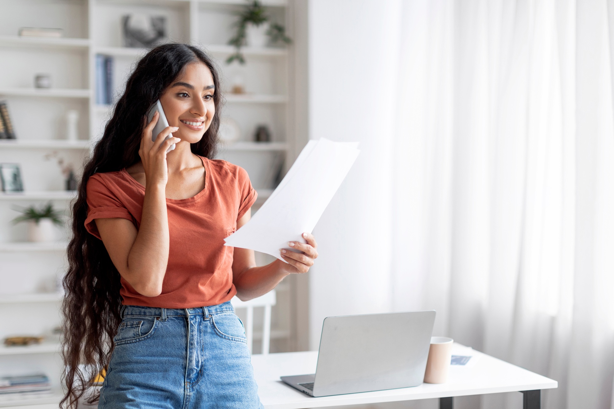 Cheerful dedicated young indian woman deeply immersed in multitasking