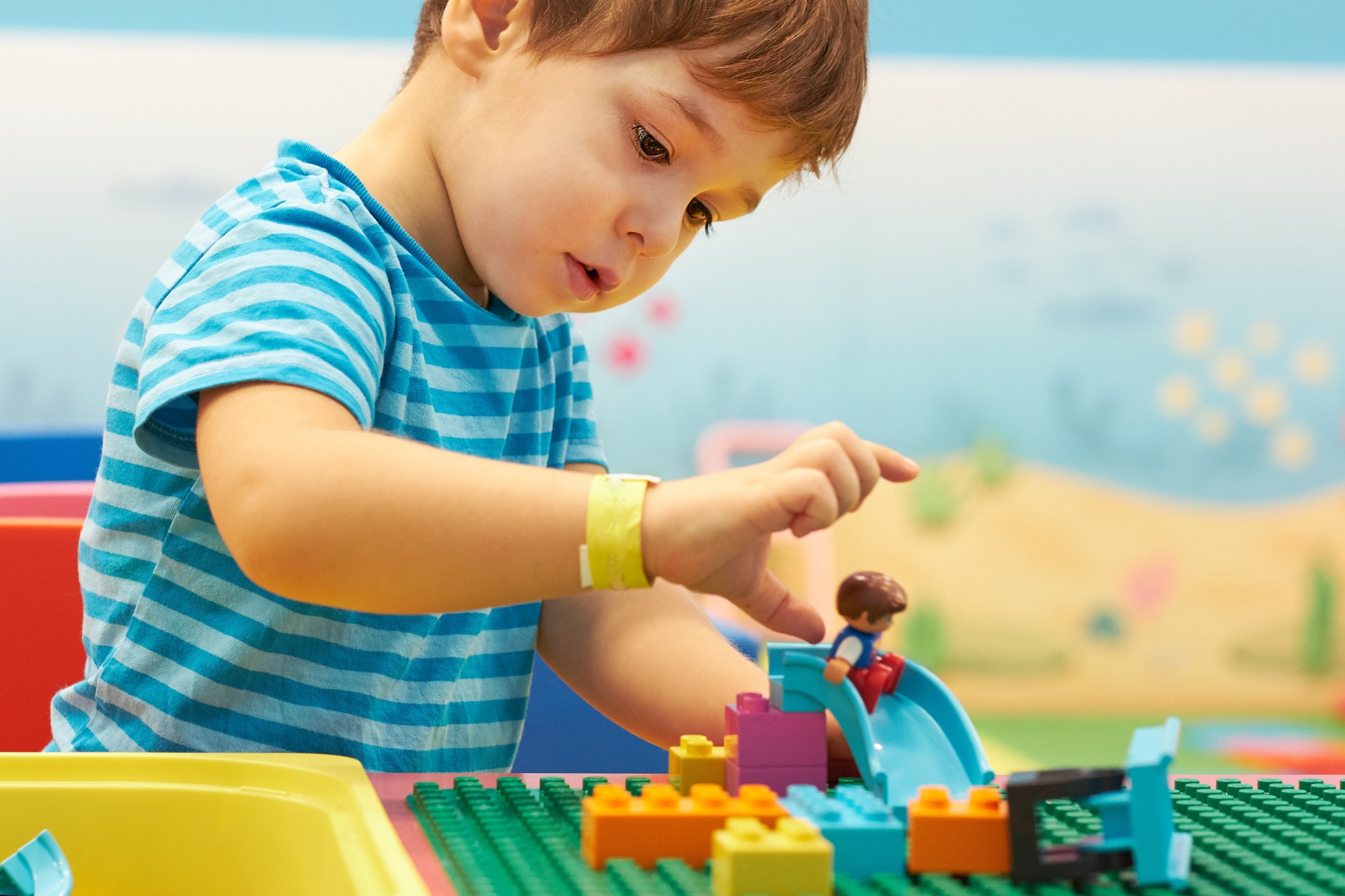 child playing and building with colorful plastic bricks table. Early learning and development.