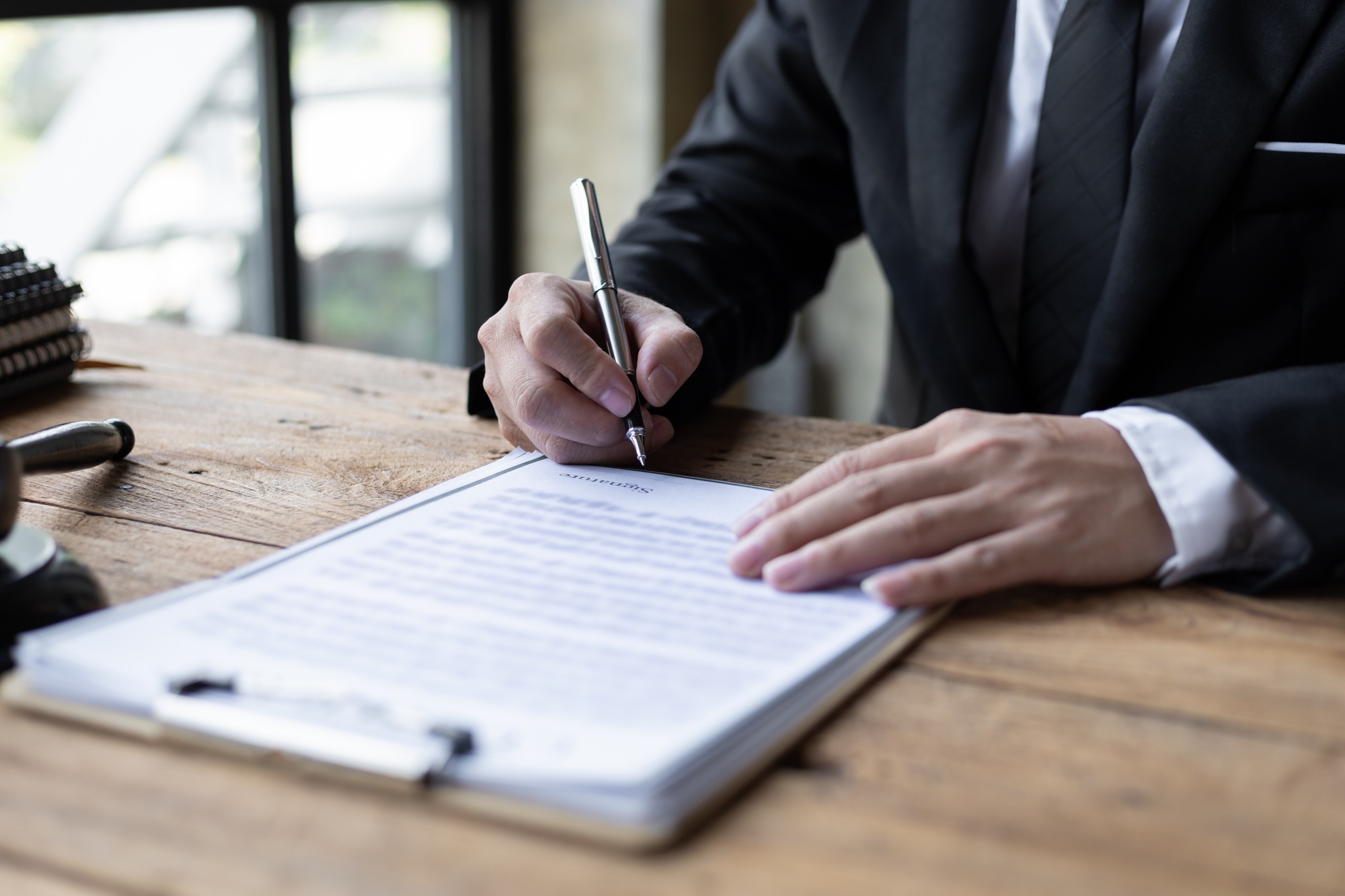 Close-up, lawyers are writing names, signing documents, contracts, legal agreements.