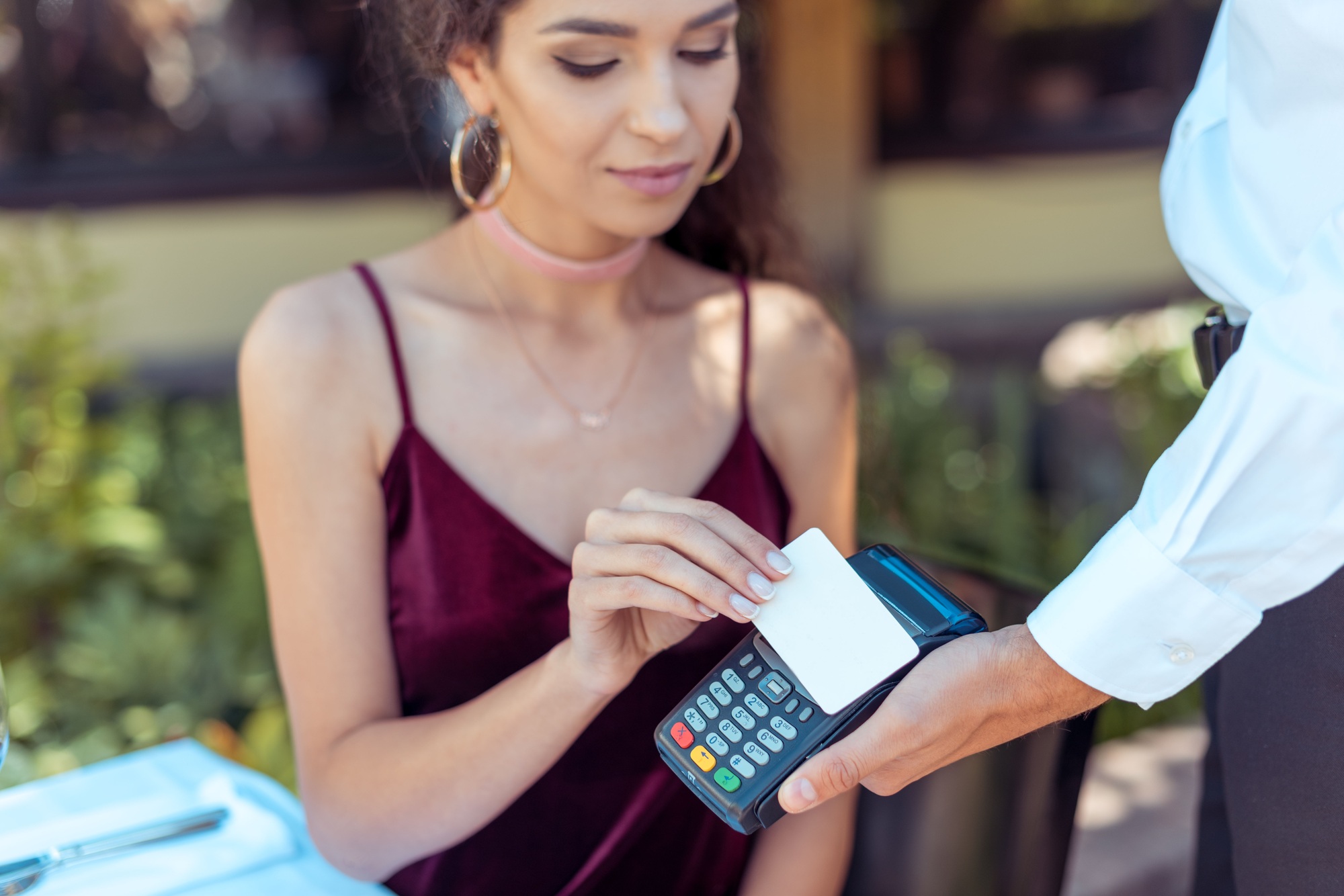 Close-up view woman using contactless credit card on pos terminal