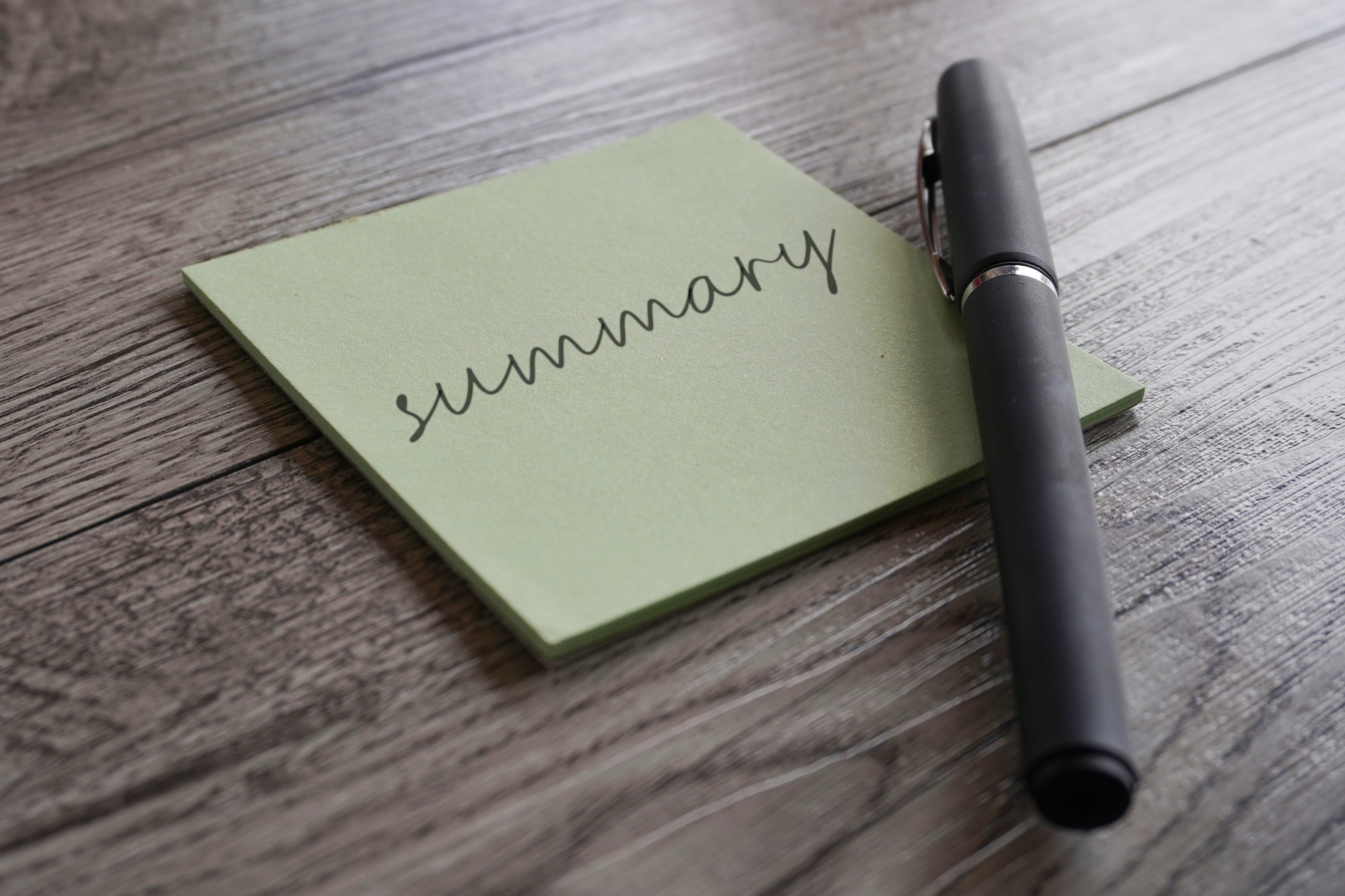 Closeup image notepad with text SUMMARY and pen.