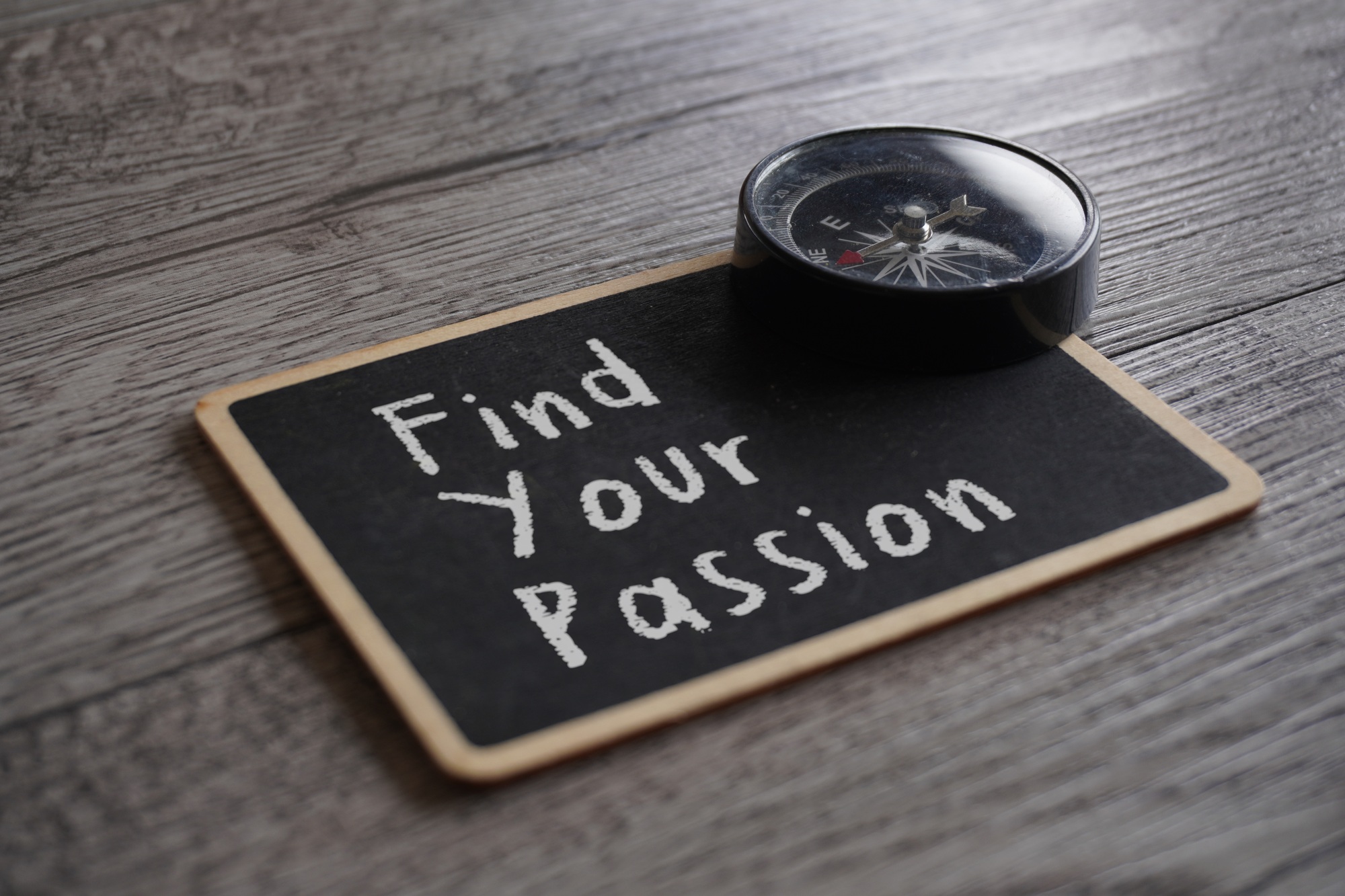 Closeup image of compass and chalkboard with text FIND YOUR PASSION.