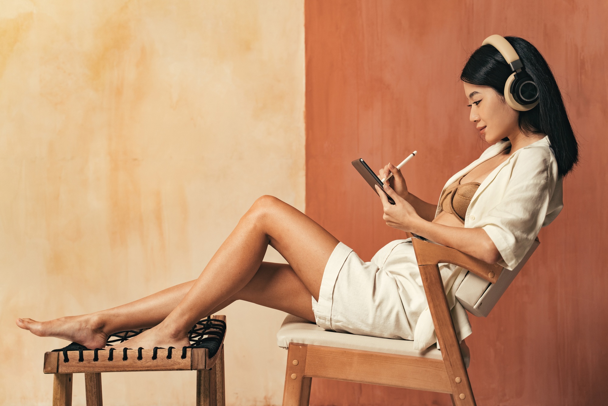 Concentrated female digital artist drawing illustrations on tablet with stylus pen in headphones