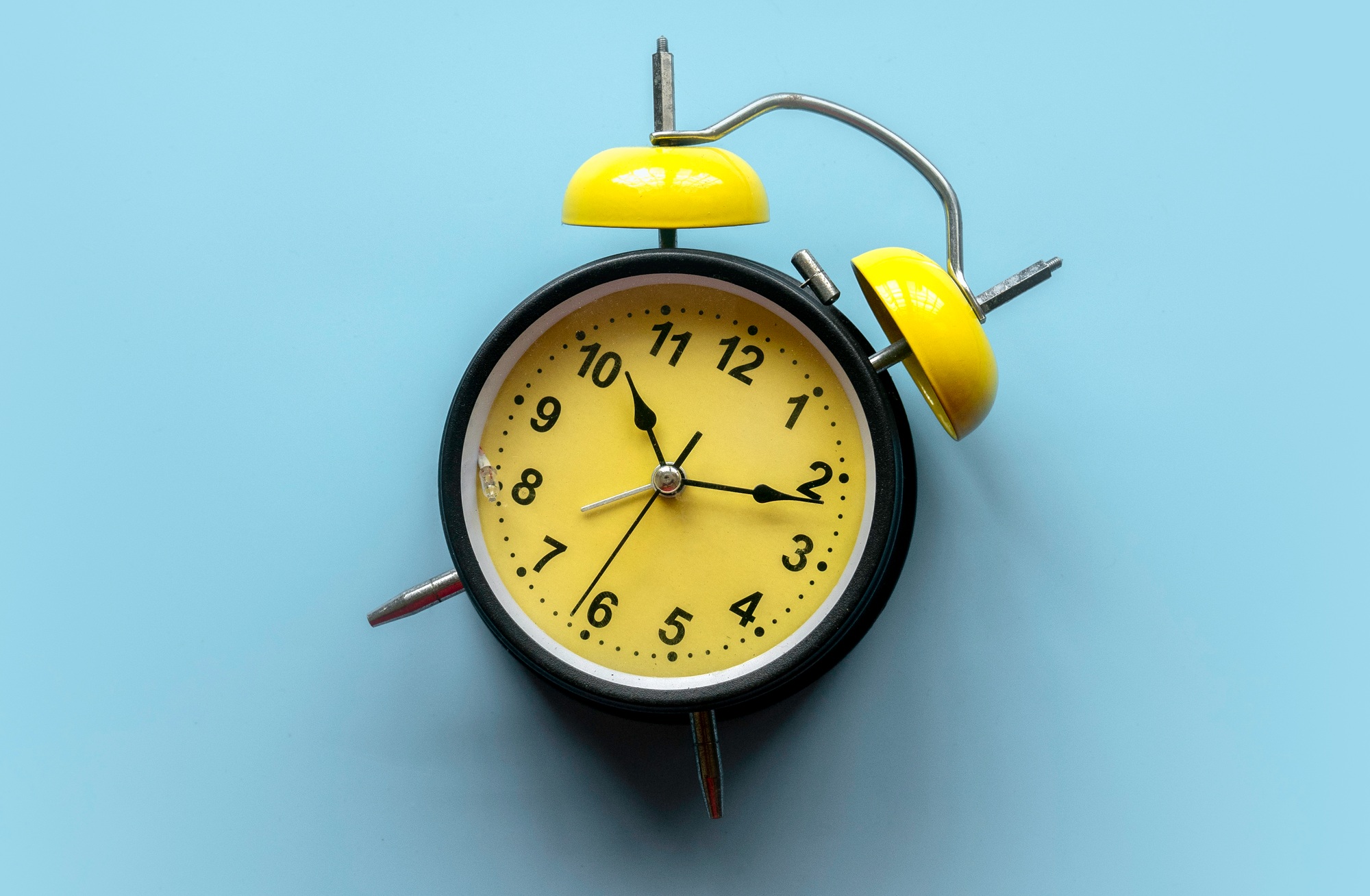 Concept of time management, deadline, work pressure. Alarm clock on blue background.