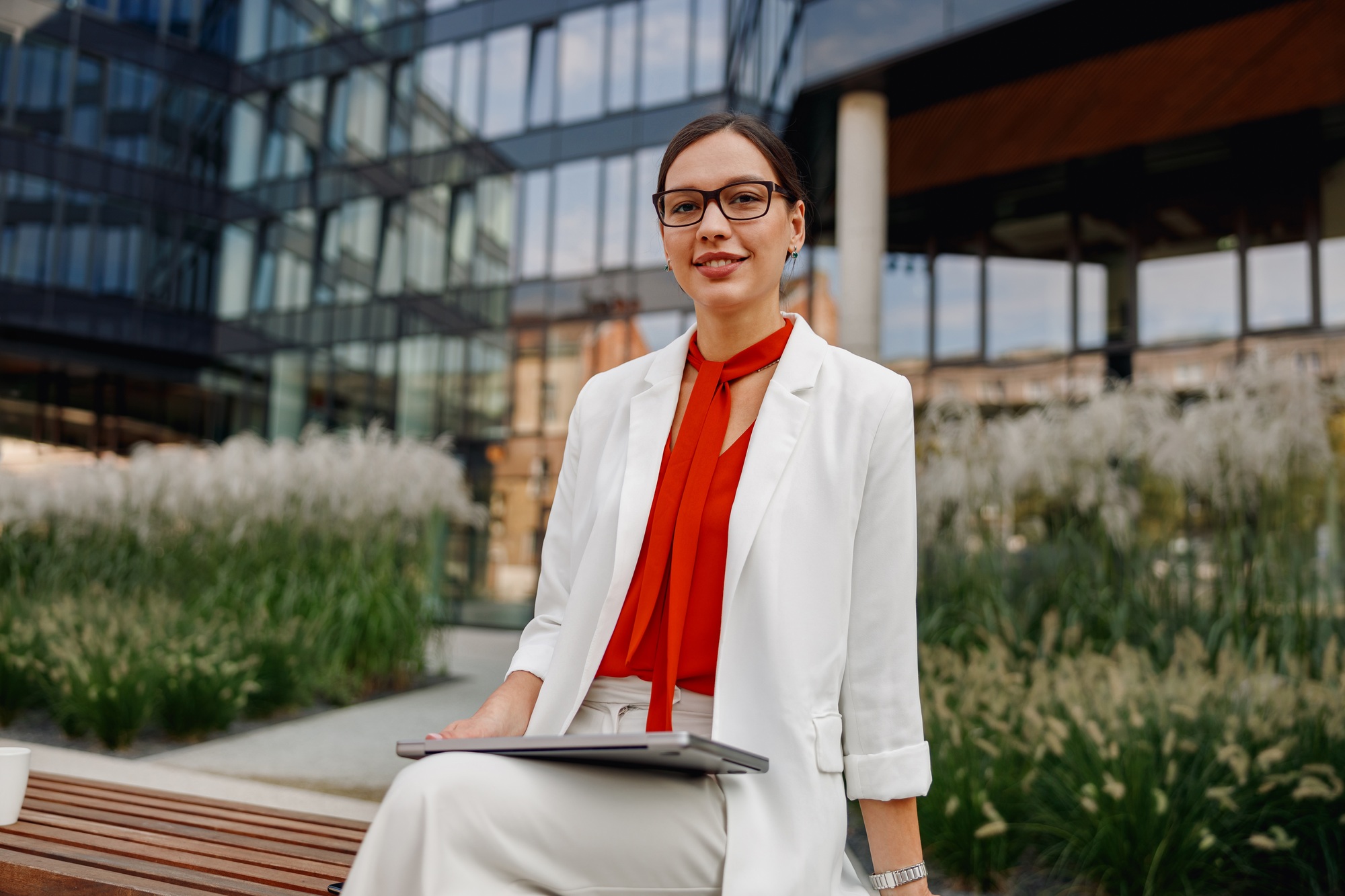 Confident Businesswoman in a Bustling Urban Setting with Her Laptop and Ambitious Goals