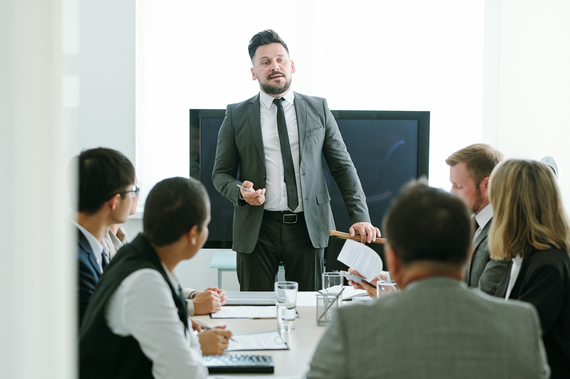 Confident middle aged businessman in formalwear making speech at training