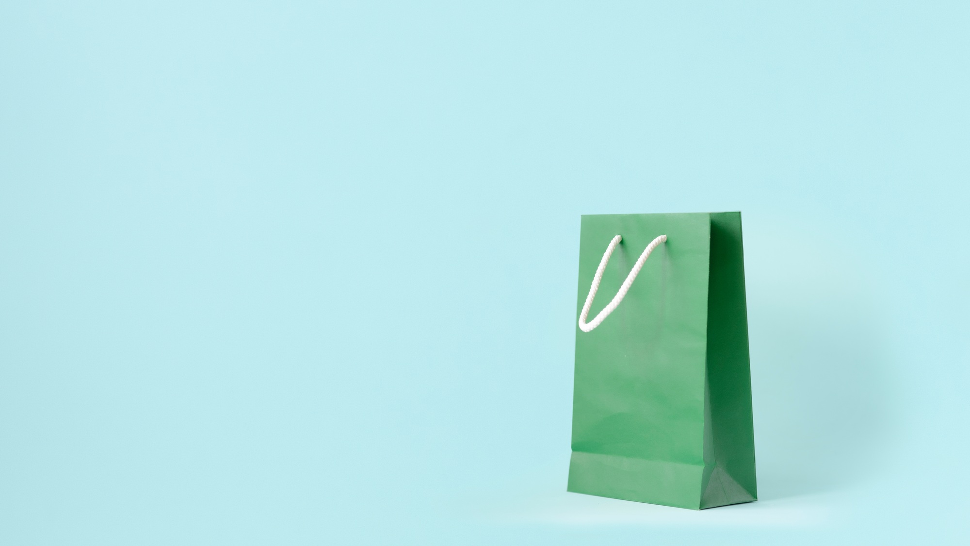 Craft paper shopping bag on blue background. store sale and consumerism. empty space concept.