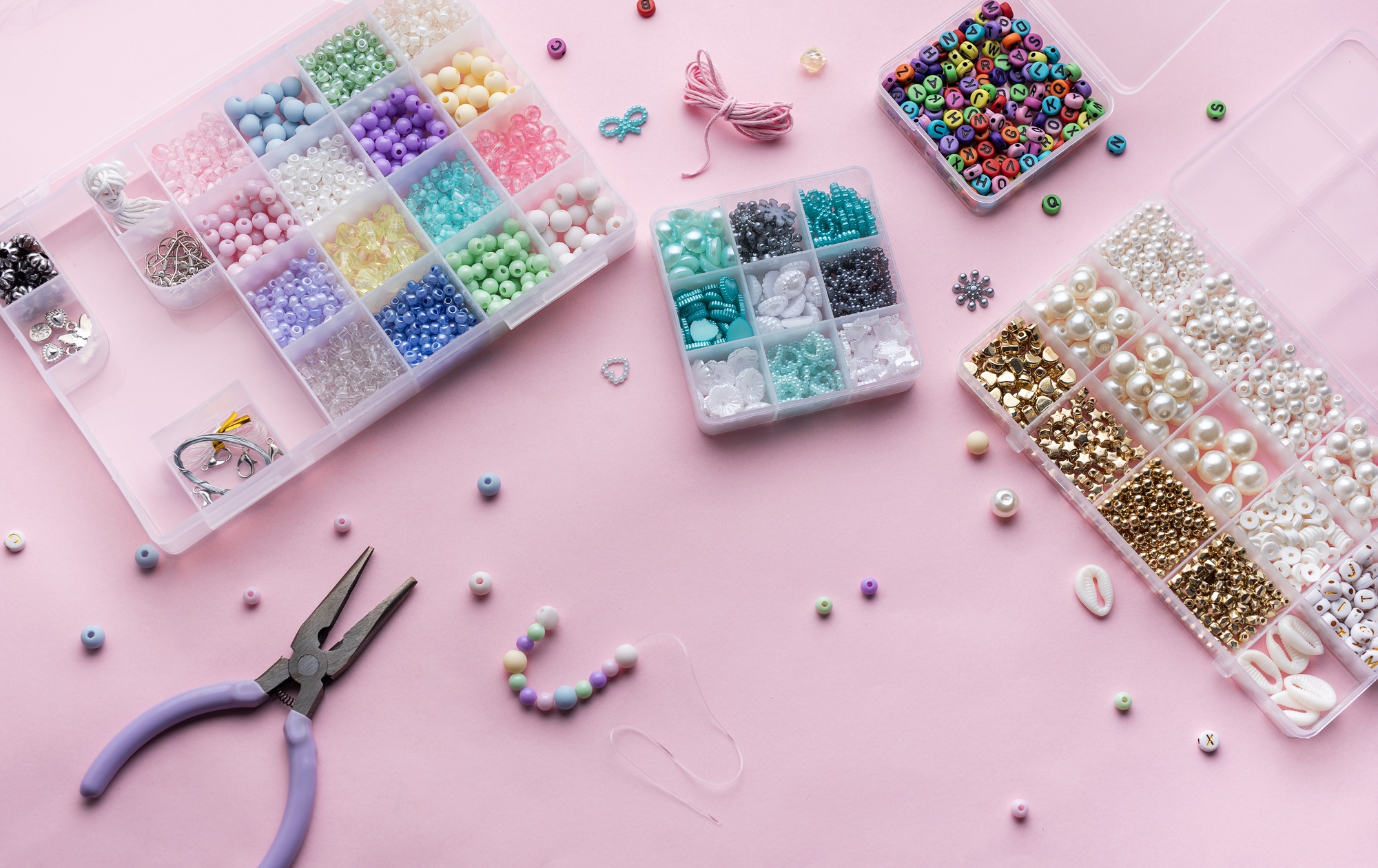 Crafting beautiful jewelry with beads and supplies on a pastel pink surface