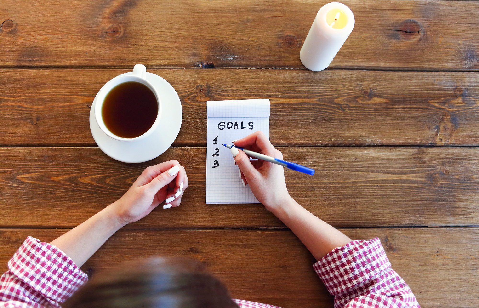 Crop woman writing goals in notepad
