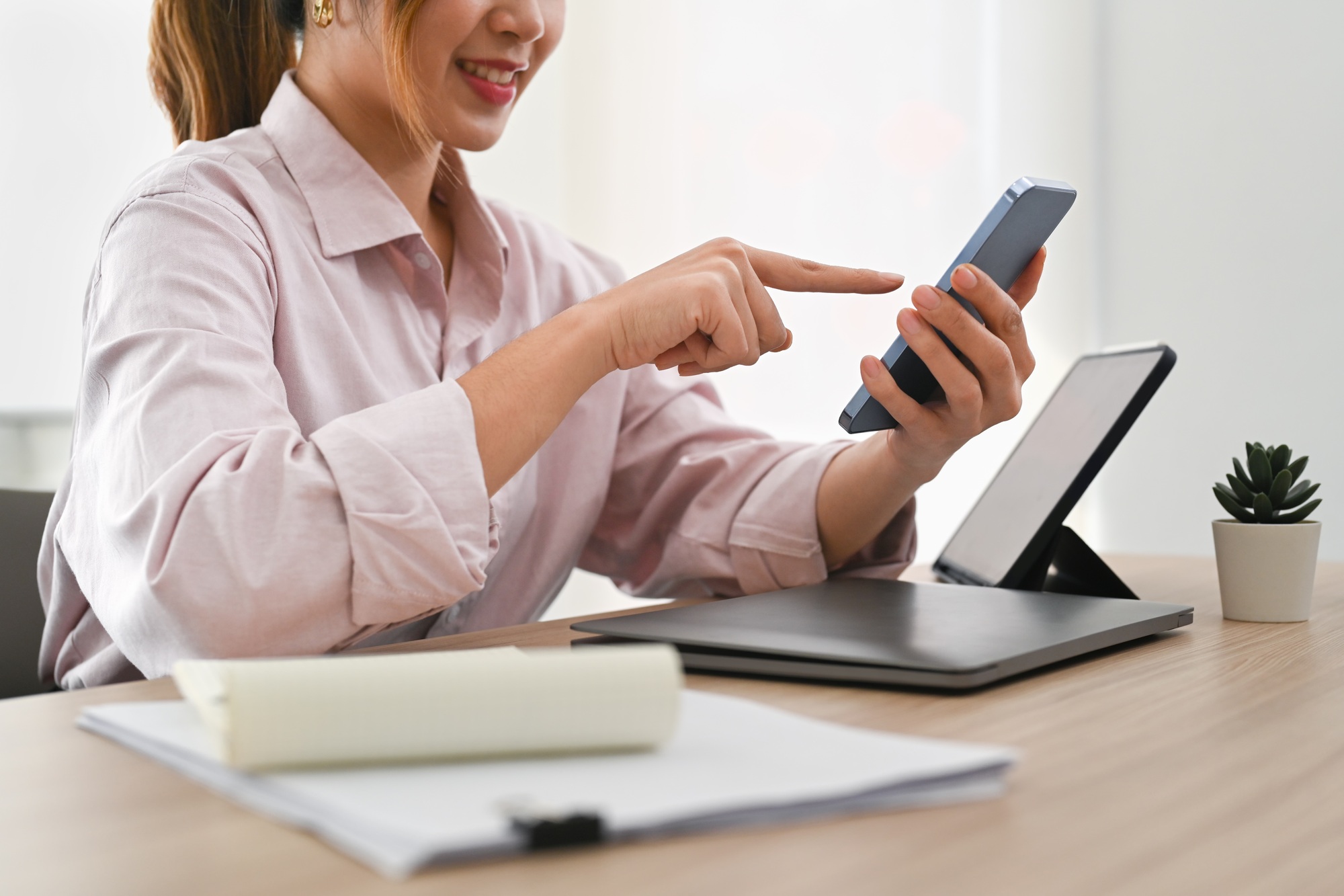 Cropped image of young businesswoman checking social app on her smart phone