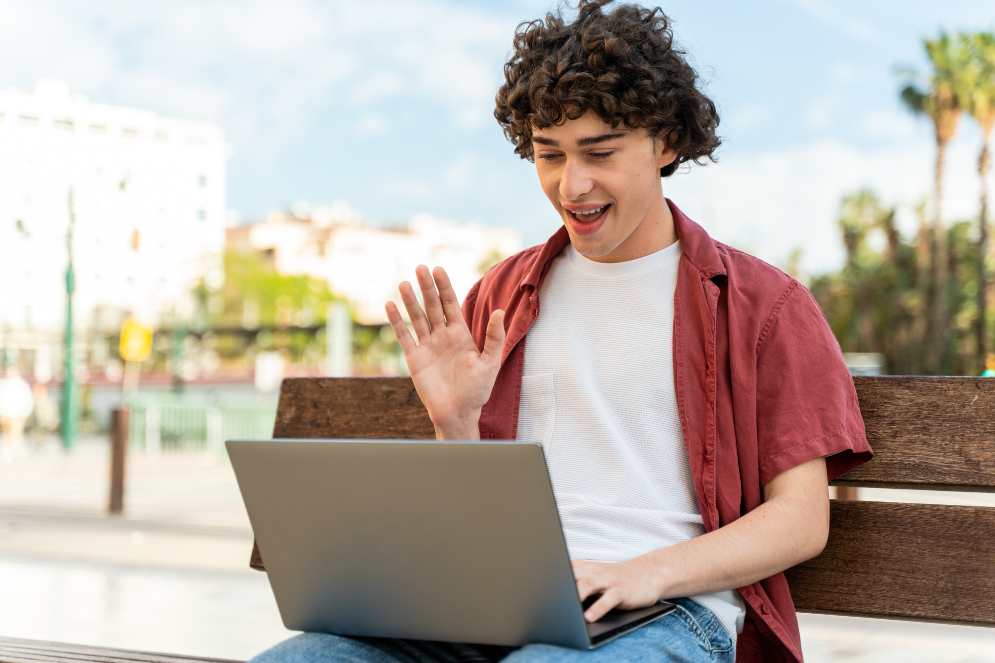 Curly man looking at the laptop screen and talking with his friend using skype