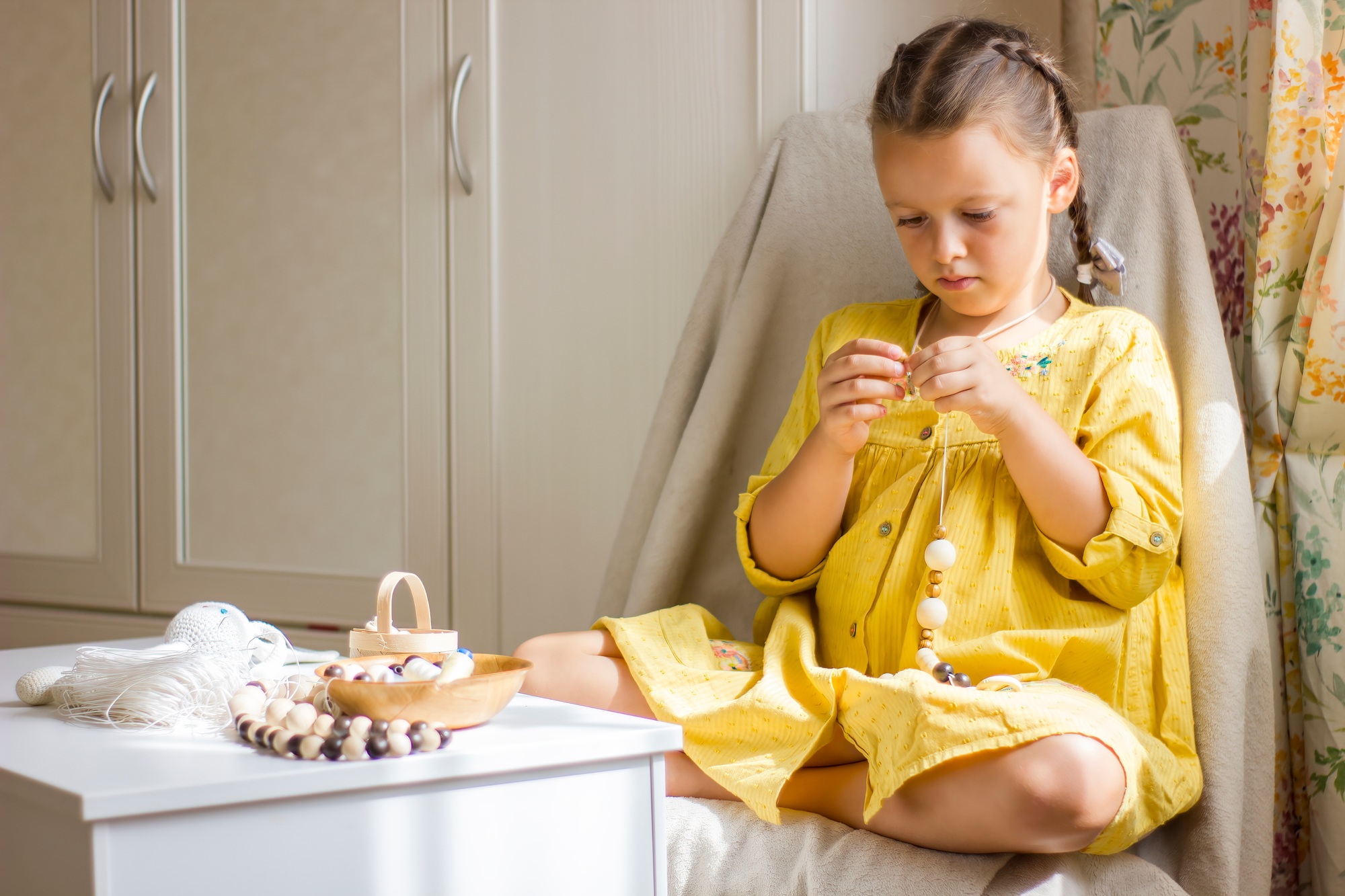 Cute little girl threading beads and making eco friendly jewelry.