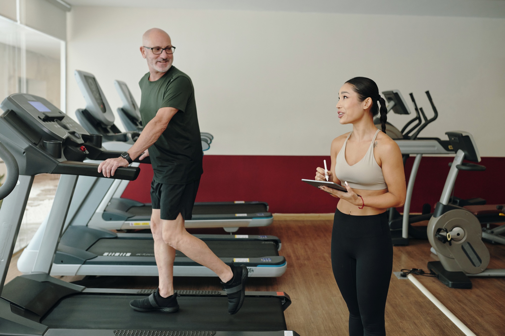 Discussing Fitness Goals While Exercising on Treadmill