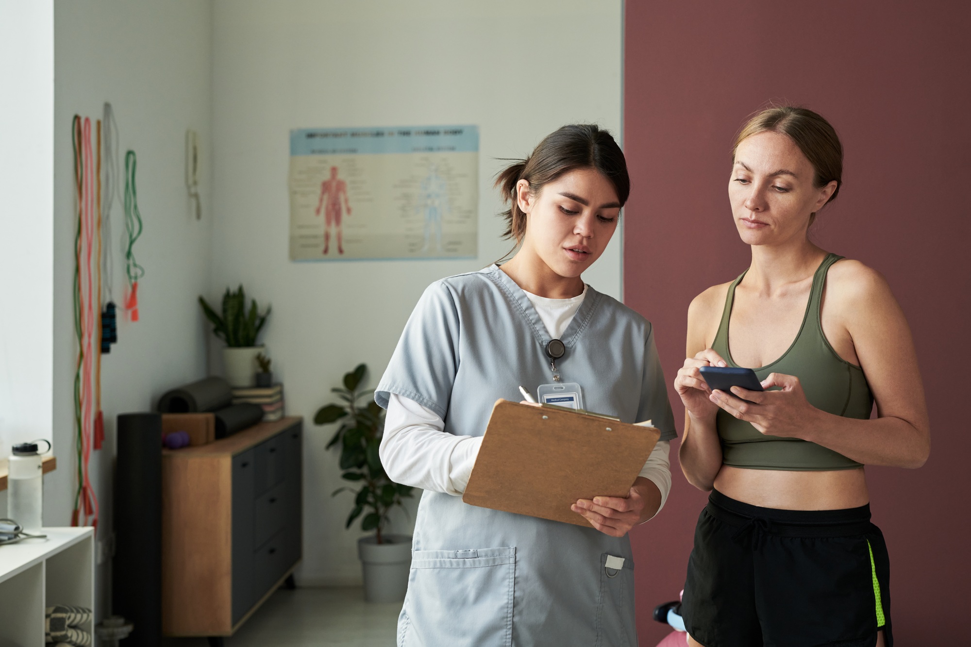 Discussing Fitness Goals With Personal Trainer in Gym