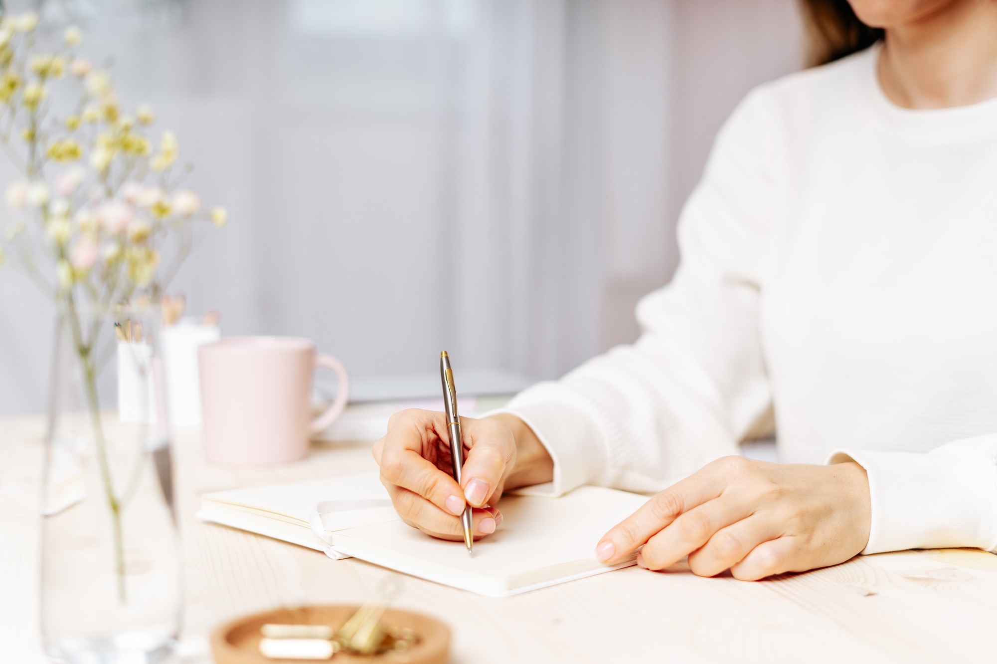 Distance learning, education and work. Woman hand holding pen on notepad at home, writes goals, plan