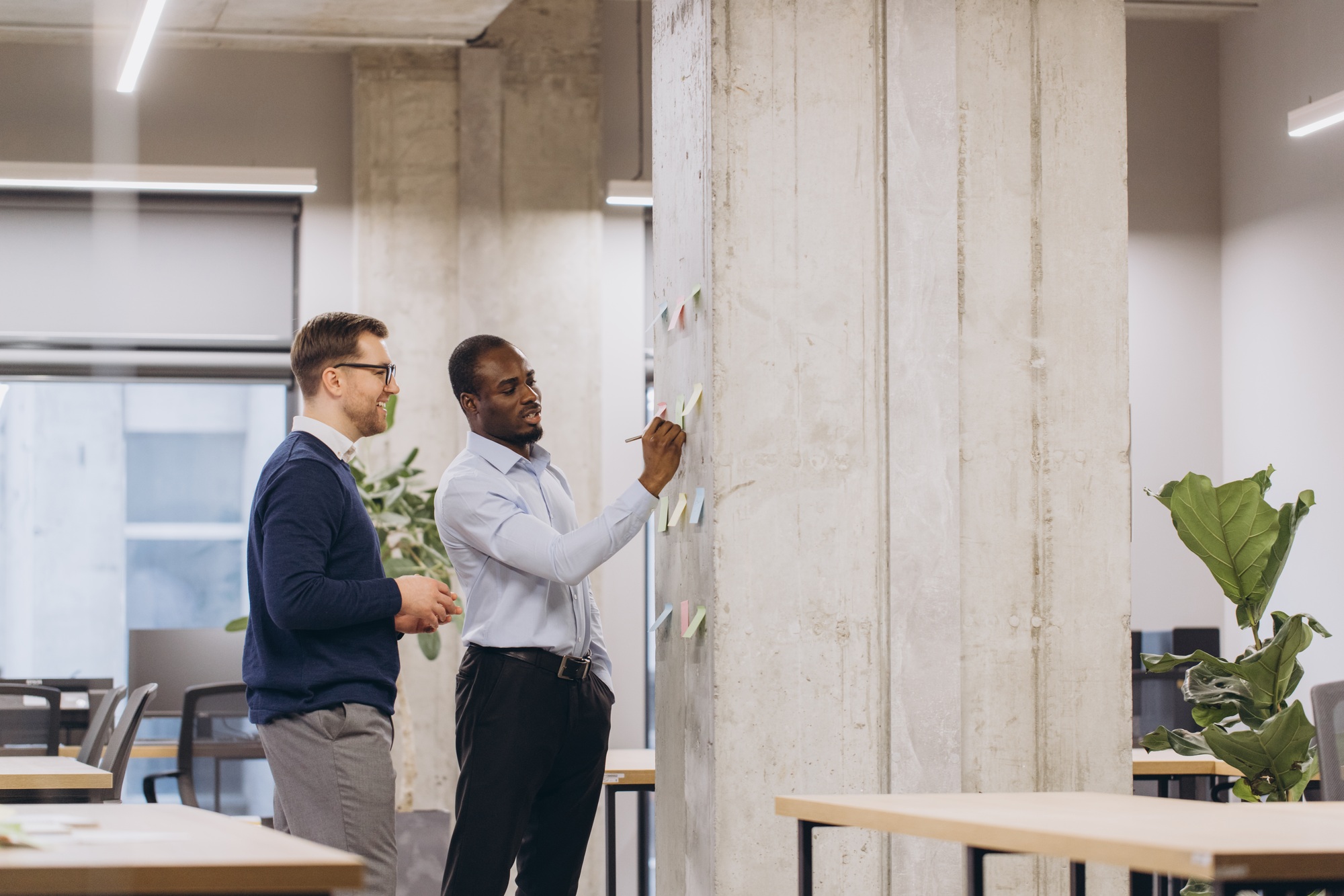 Diverse businesspeople collaborating, noting strategic concepts on glass wall