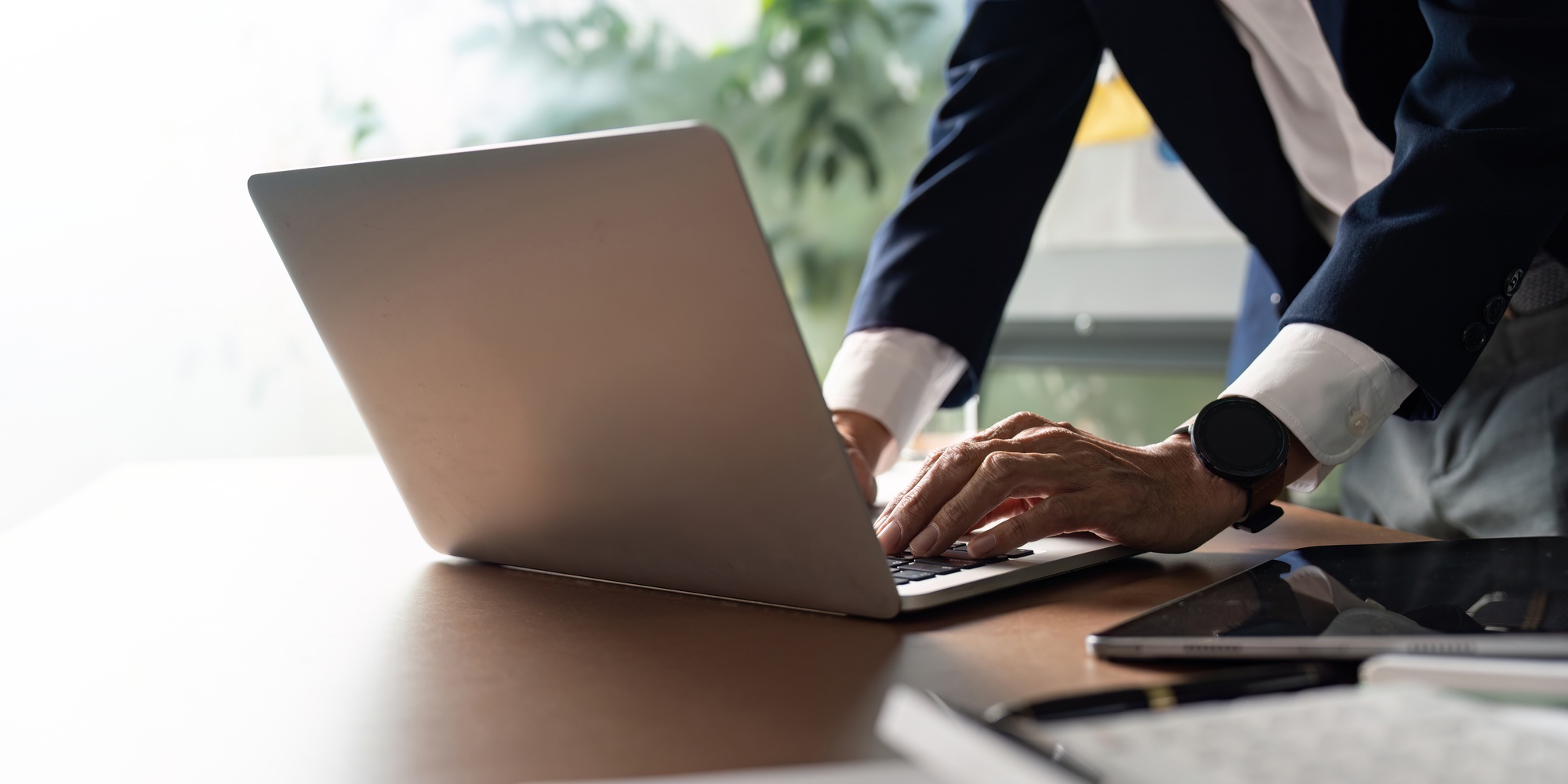 Elderly professional typing on laptop for business analysis and planning.