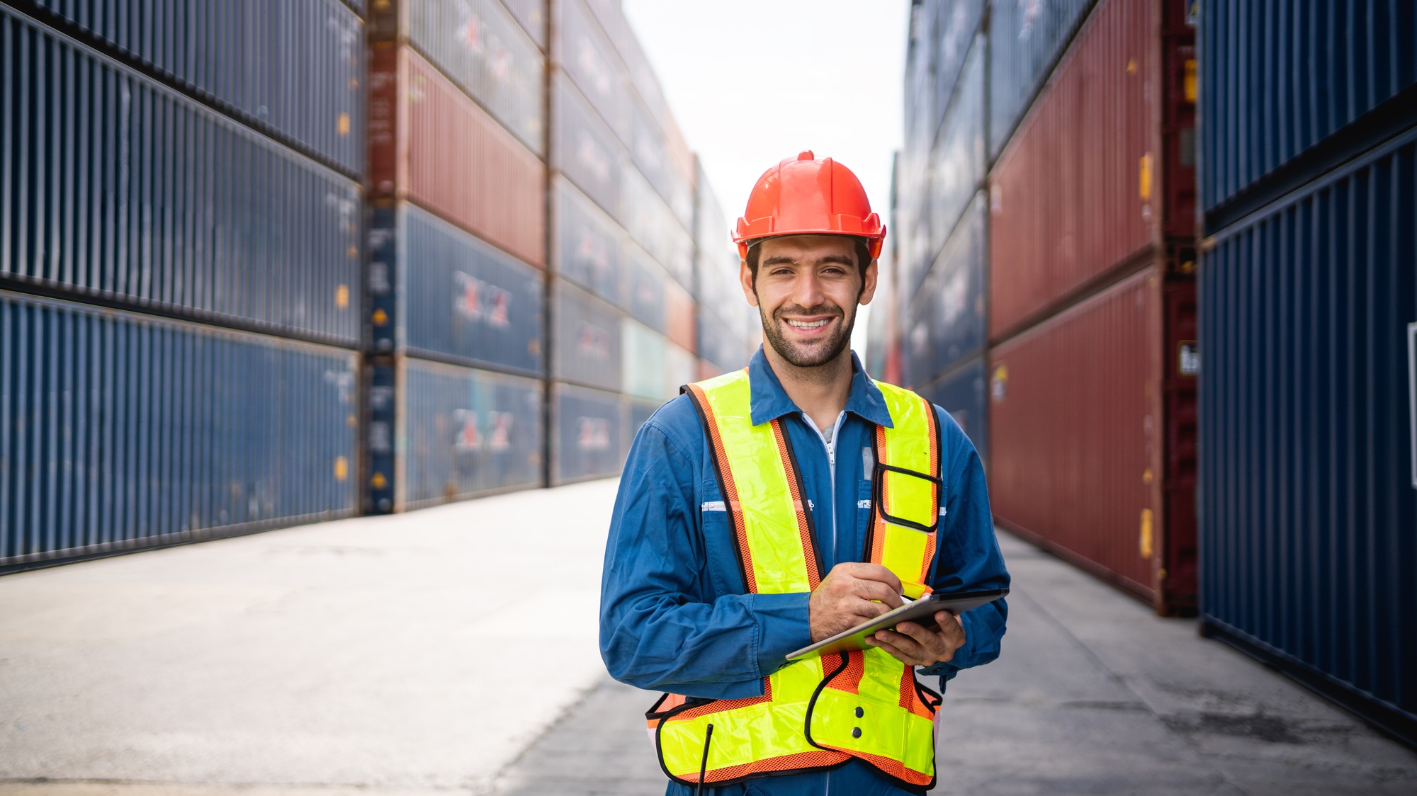 Engineer or foreman checking inventory or task details at container yard warehouse.