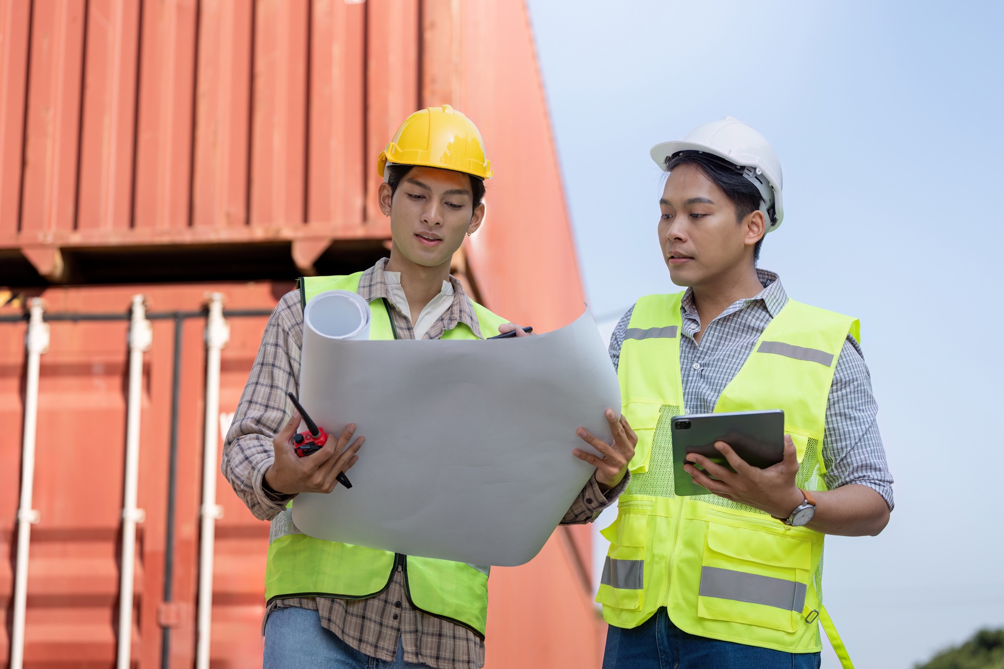 Engineers reviewing blueprints for logistics and container management in import and export