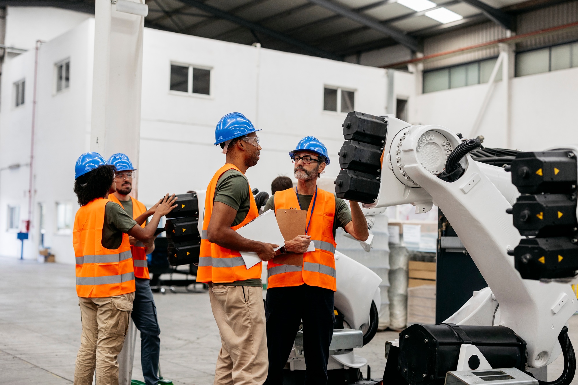 Engineers working and programming a robot arm in a factory