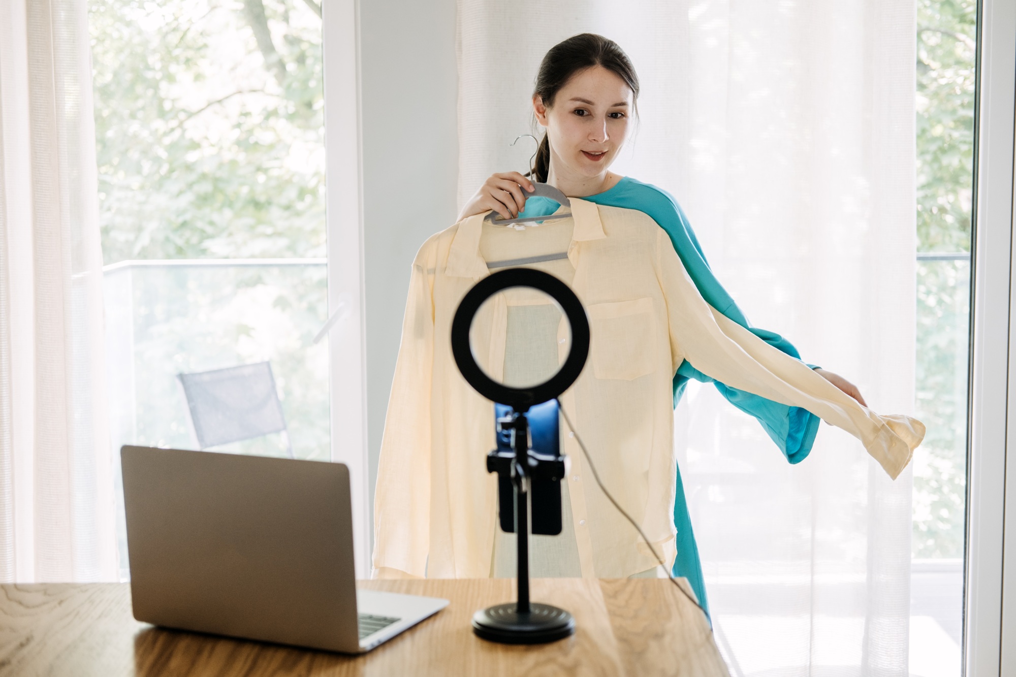 Fashion influencer showcasing yellow blouse with ring light and laptop, online content creation