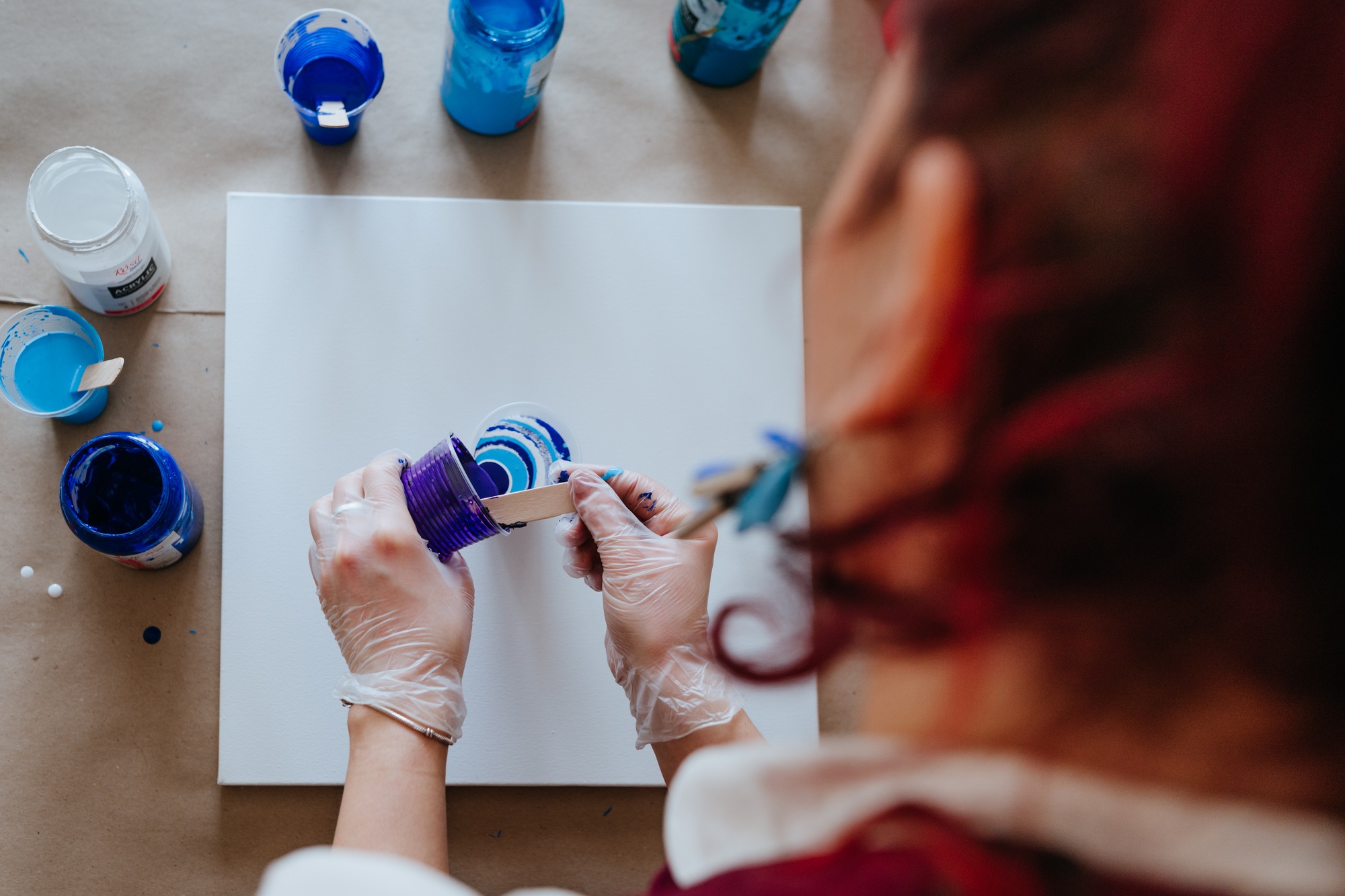 Female artist mixing acryl paintsin the glass painting picture working in fluid art technique