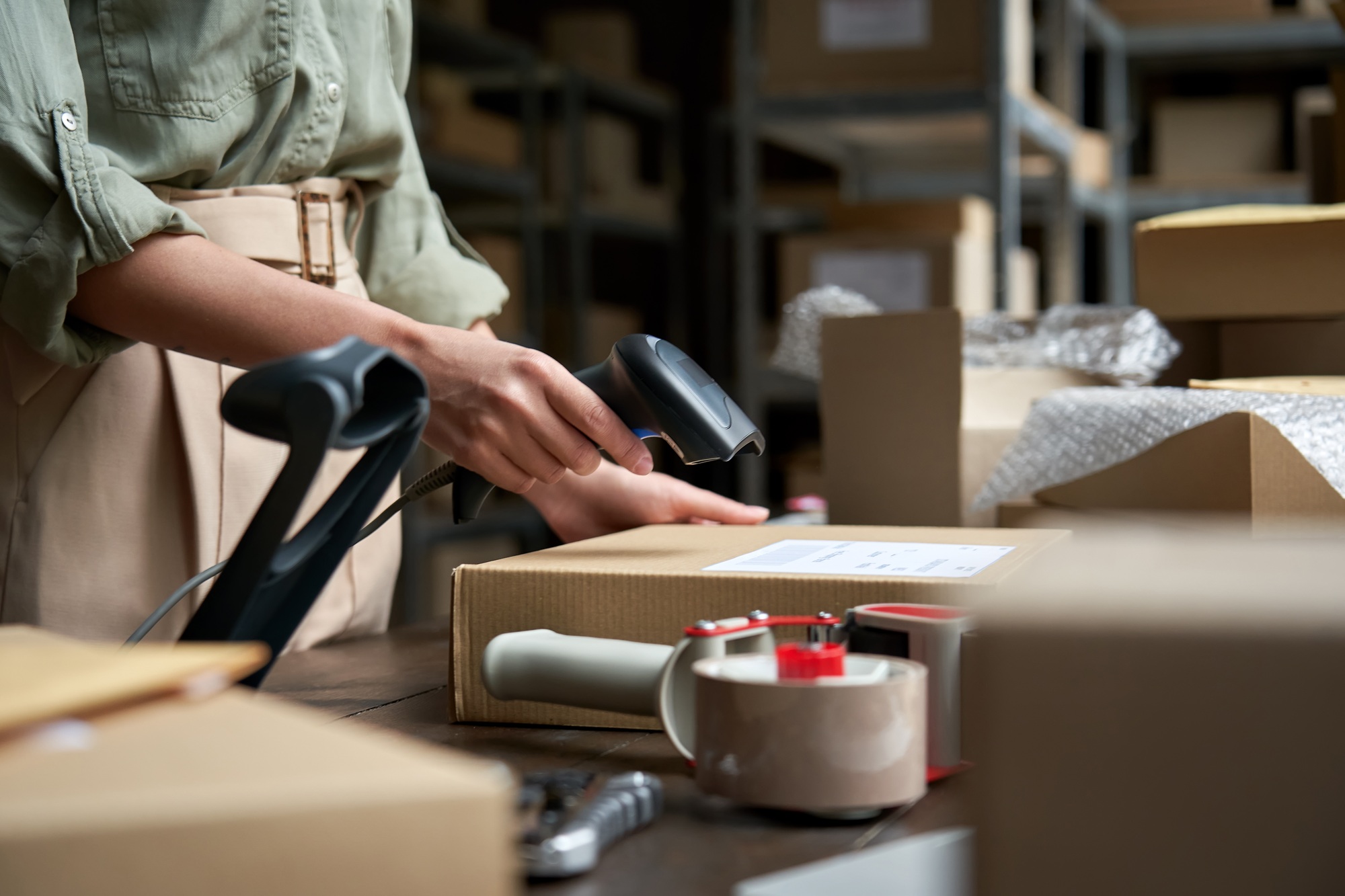 Female seller scanning ecommerce shipping box in dropshipping warehouse.