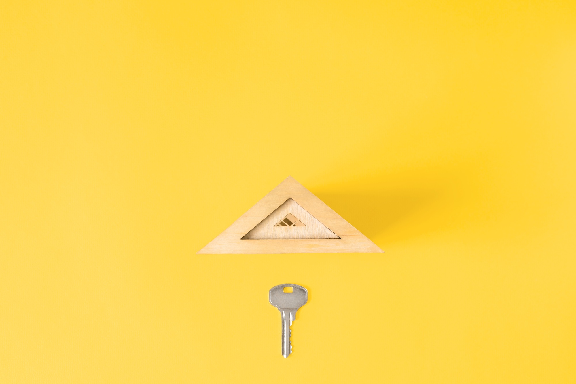 Flat lay metal key and toy roof, copy space. Creative concept of buying (selling) a house, renting