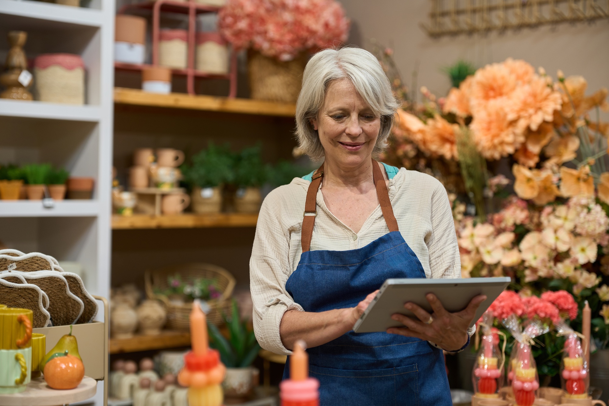 Florist using digital tablet and managing inventory in flower shop