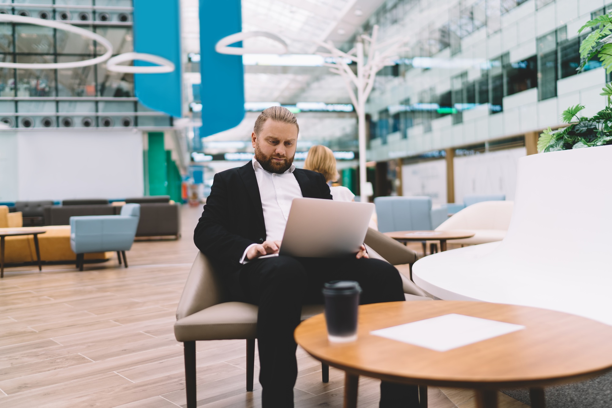 Focused businessman working on laptop while sitting at table with coffee cup
