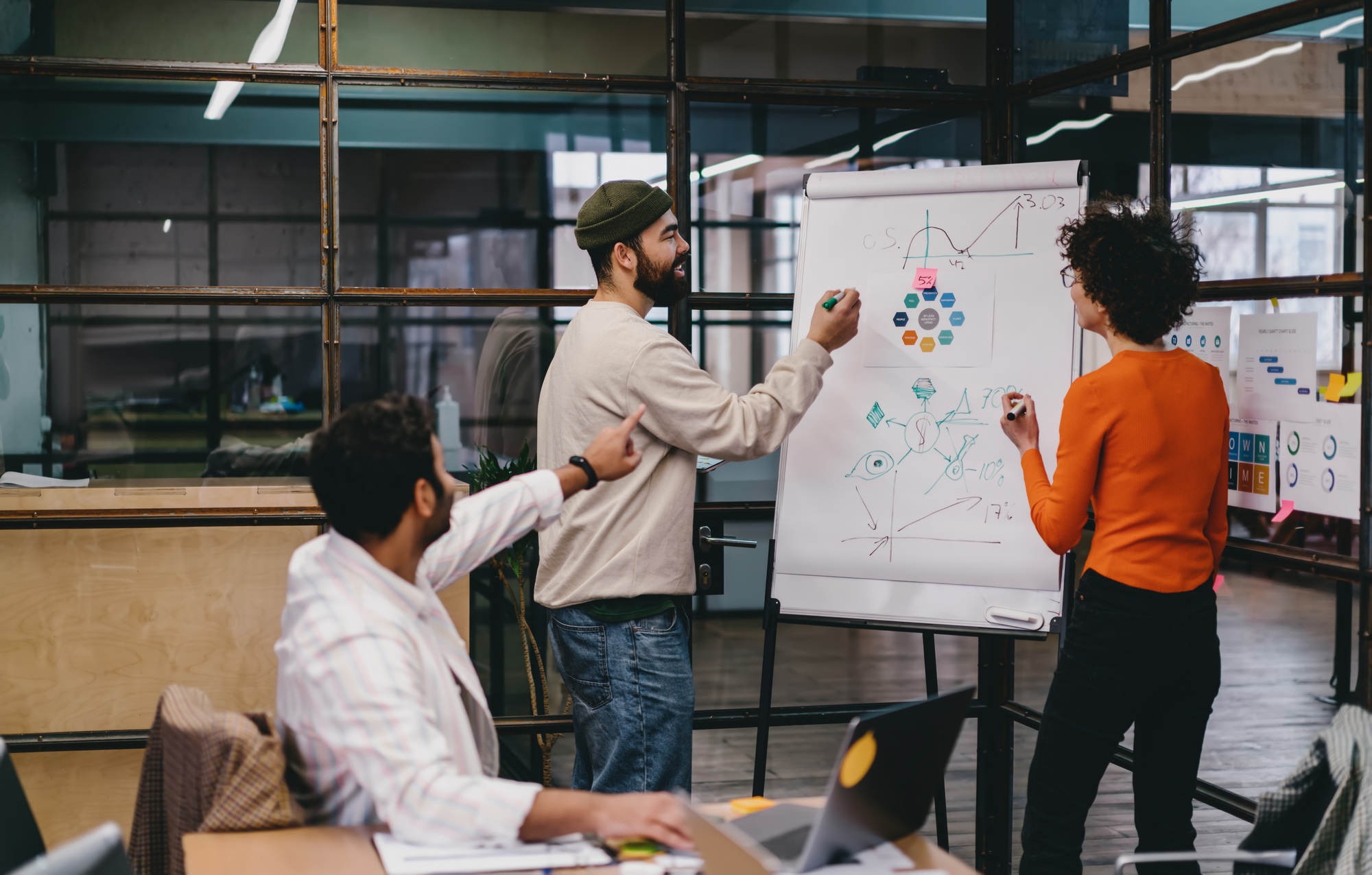 Focused diverse colleagues discussing project on board in office