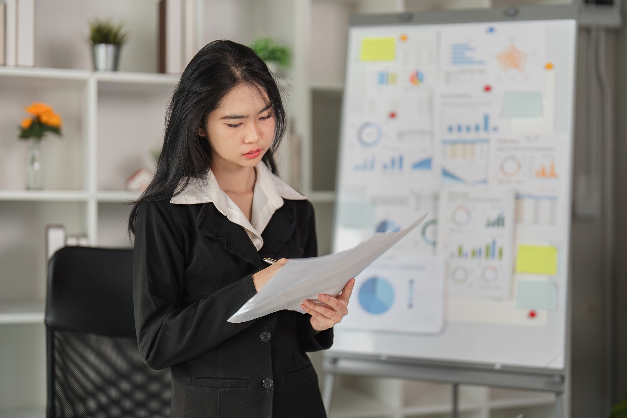 Focused document assessment. Young professional evaluating financial reports in her office.