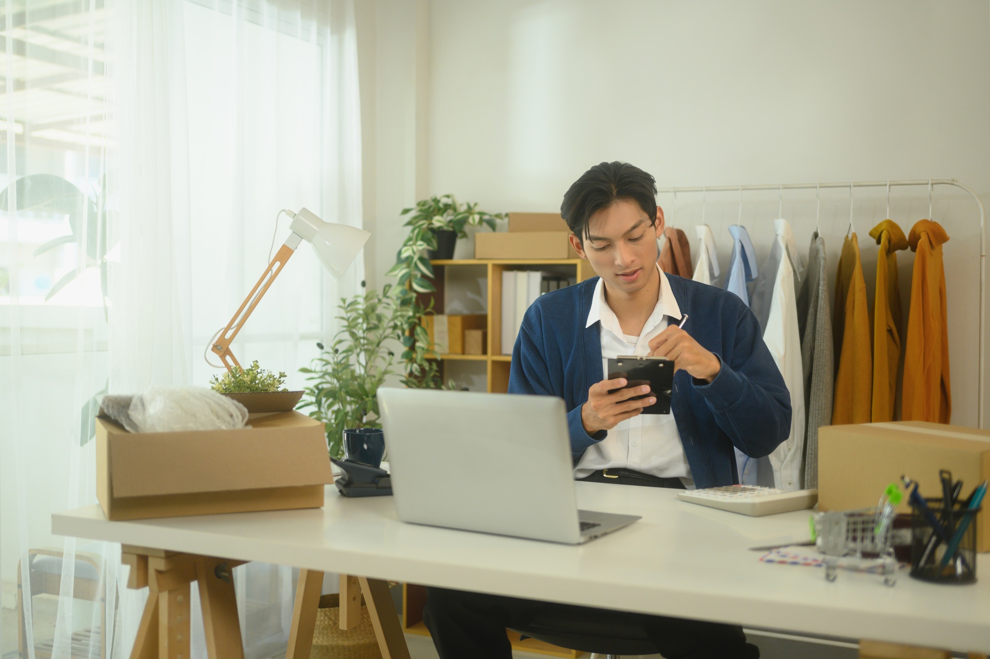 Focused small business owner working on inventory and financial planning in a bright workspace
