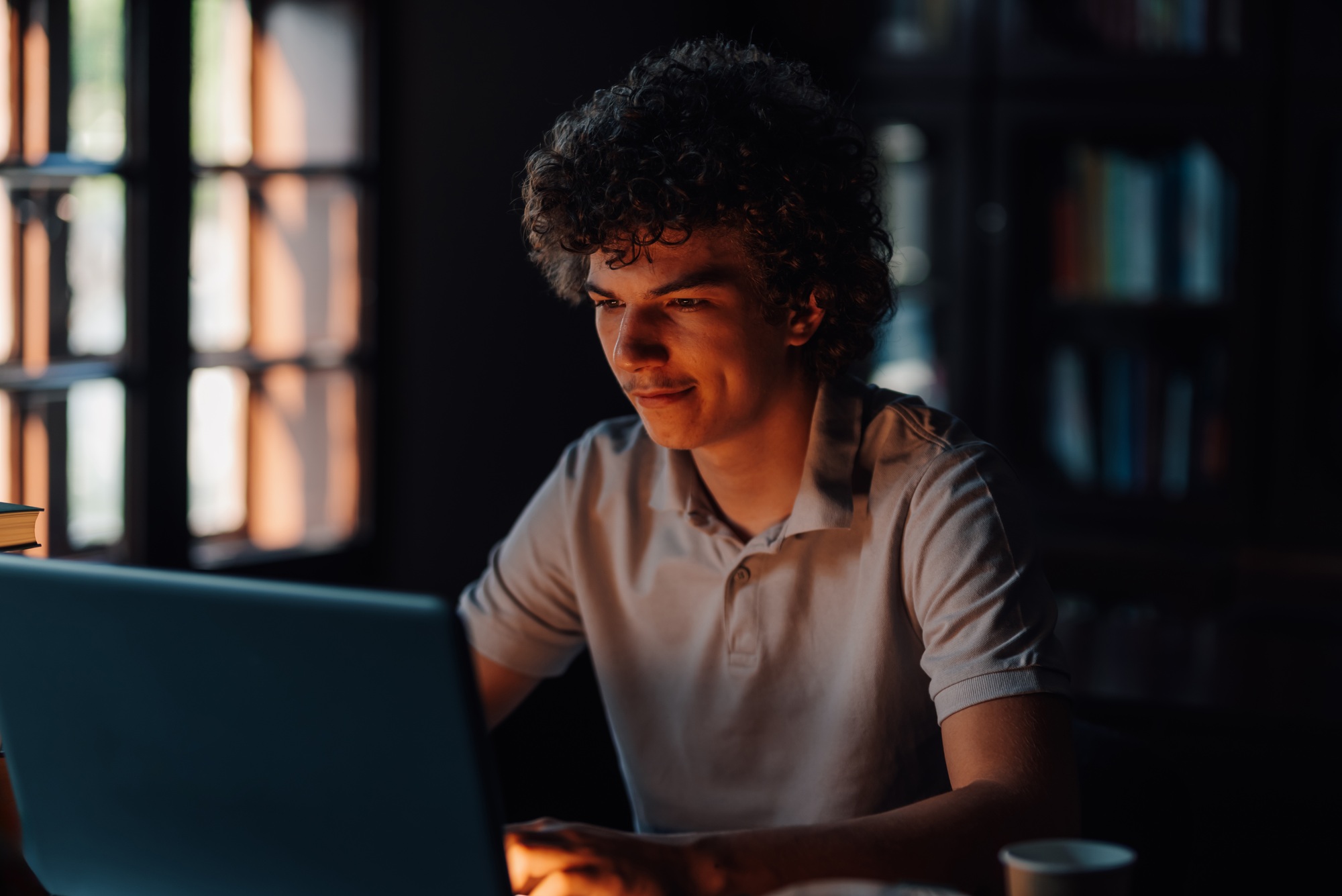 Focused student working on laptop in cozy library setting