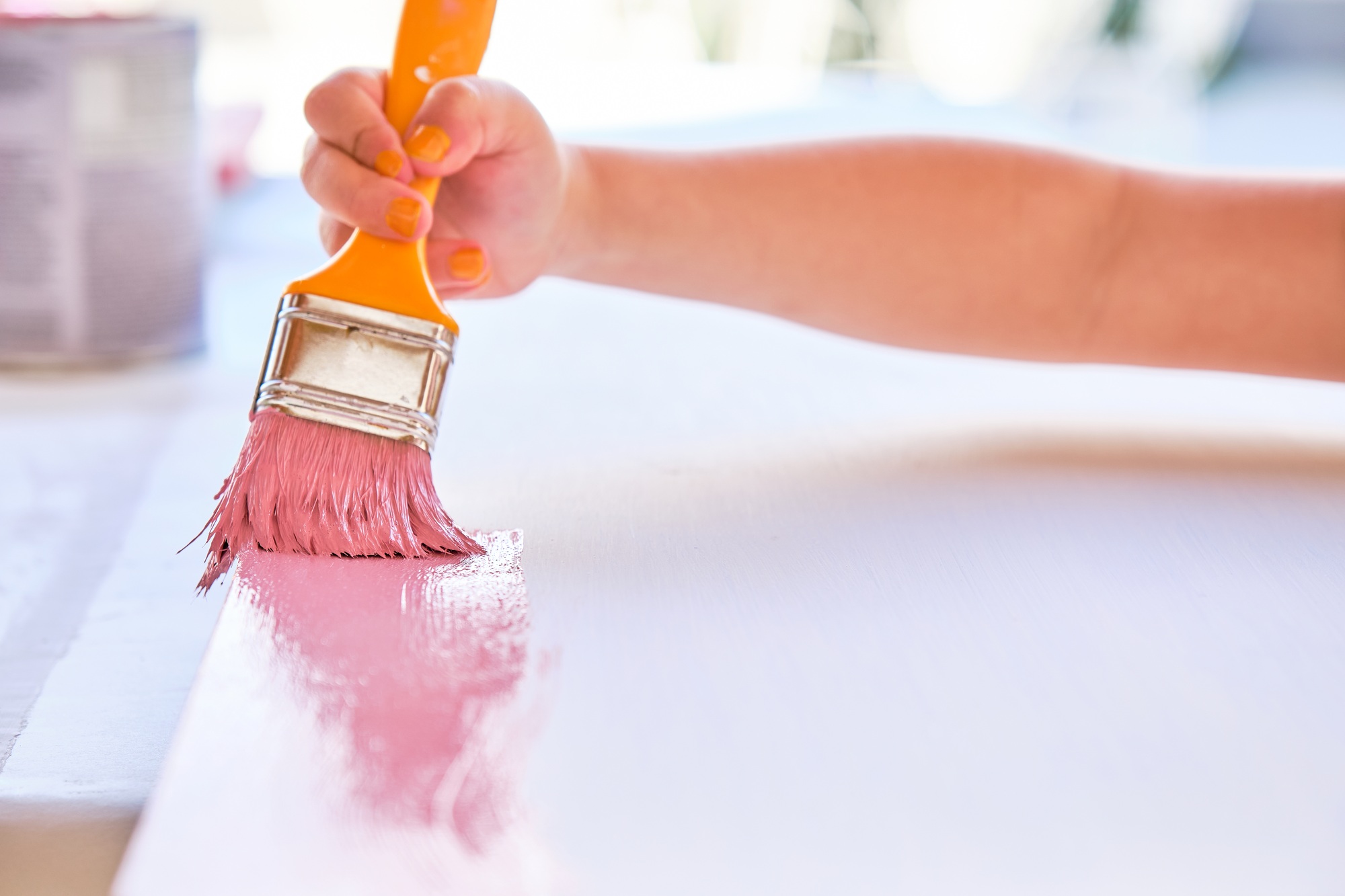 girl's hand painting a pink wood with a brush