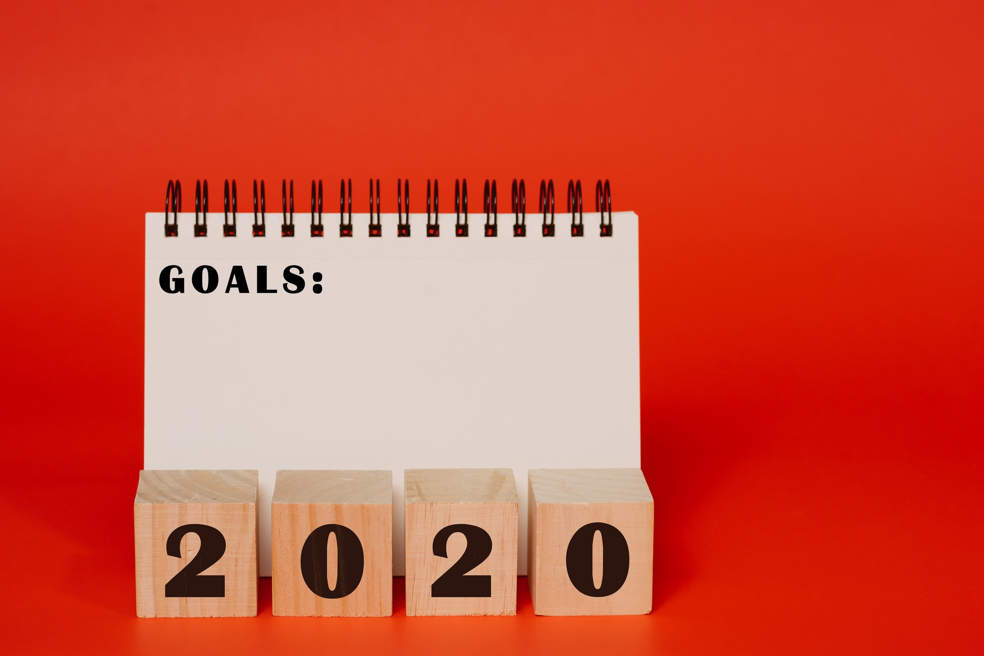 Goals, planning concept, 2020 on wooden blocks and goals written in notebook against red background