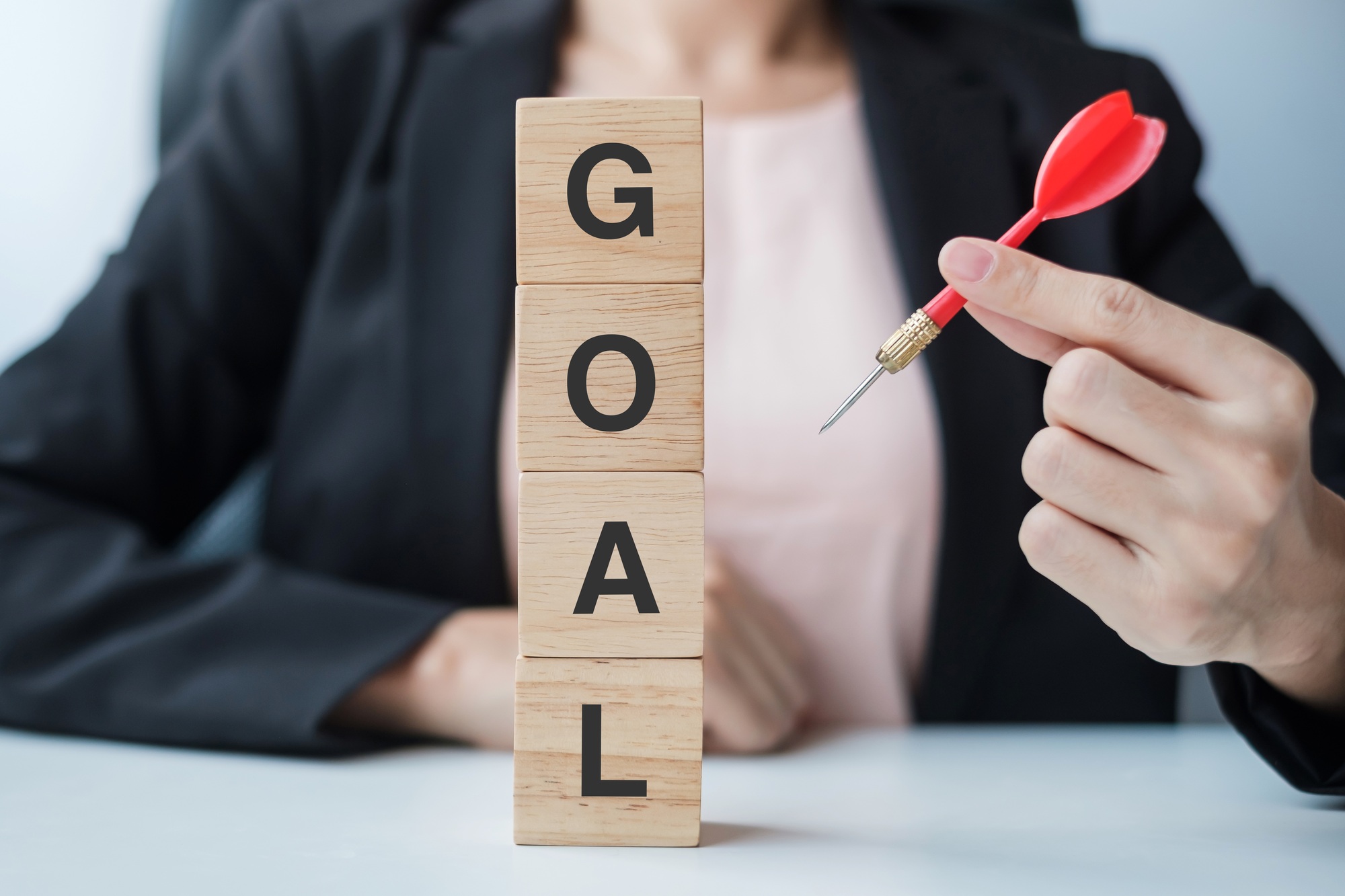 Hand holding red dart over Goal block. target, aim, objective, leadership, Business and marketing