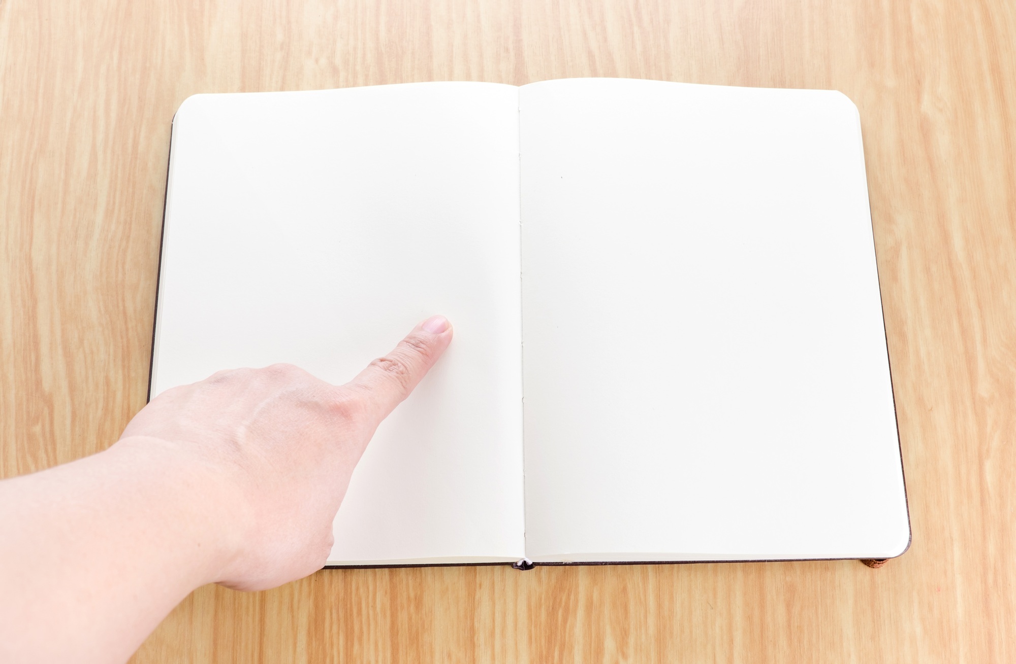 Hand pointing on blank open notebook lay it on wooden table,Template mock up for adding your text