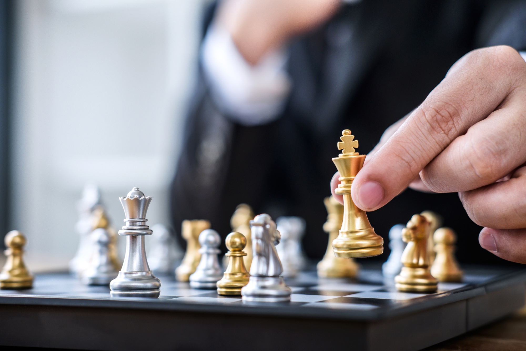 Hands of confident businessman playing chess game to development analysis new strategy plan