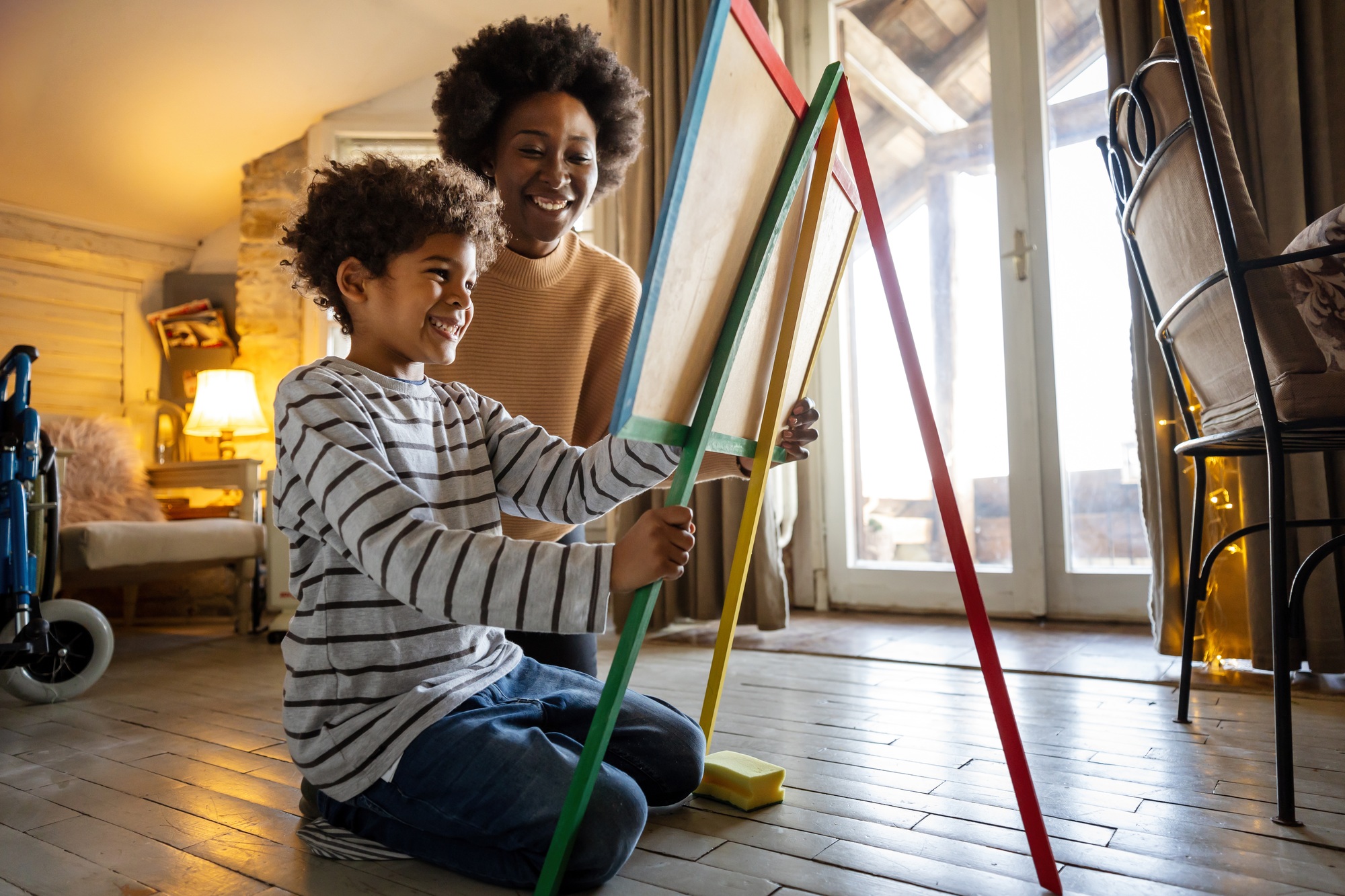 Happy black woman play and learning with little kid at home. Education children development concept