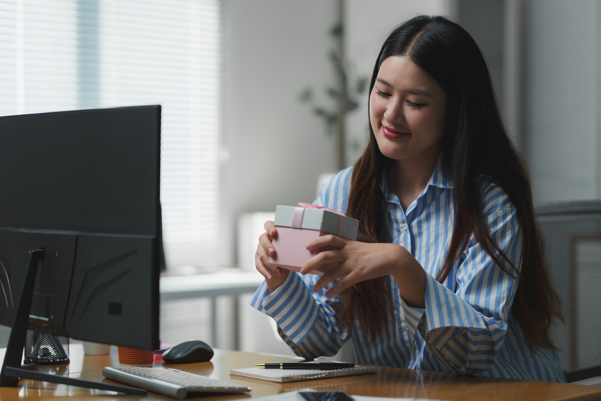 Happy businesswoman holding a gift in office: appreciation and recognition