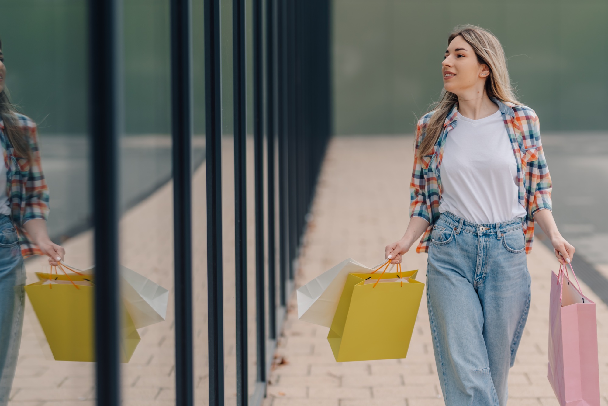 Happy customer walking with shopping bags near mall window display